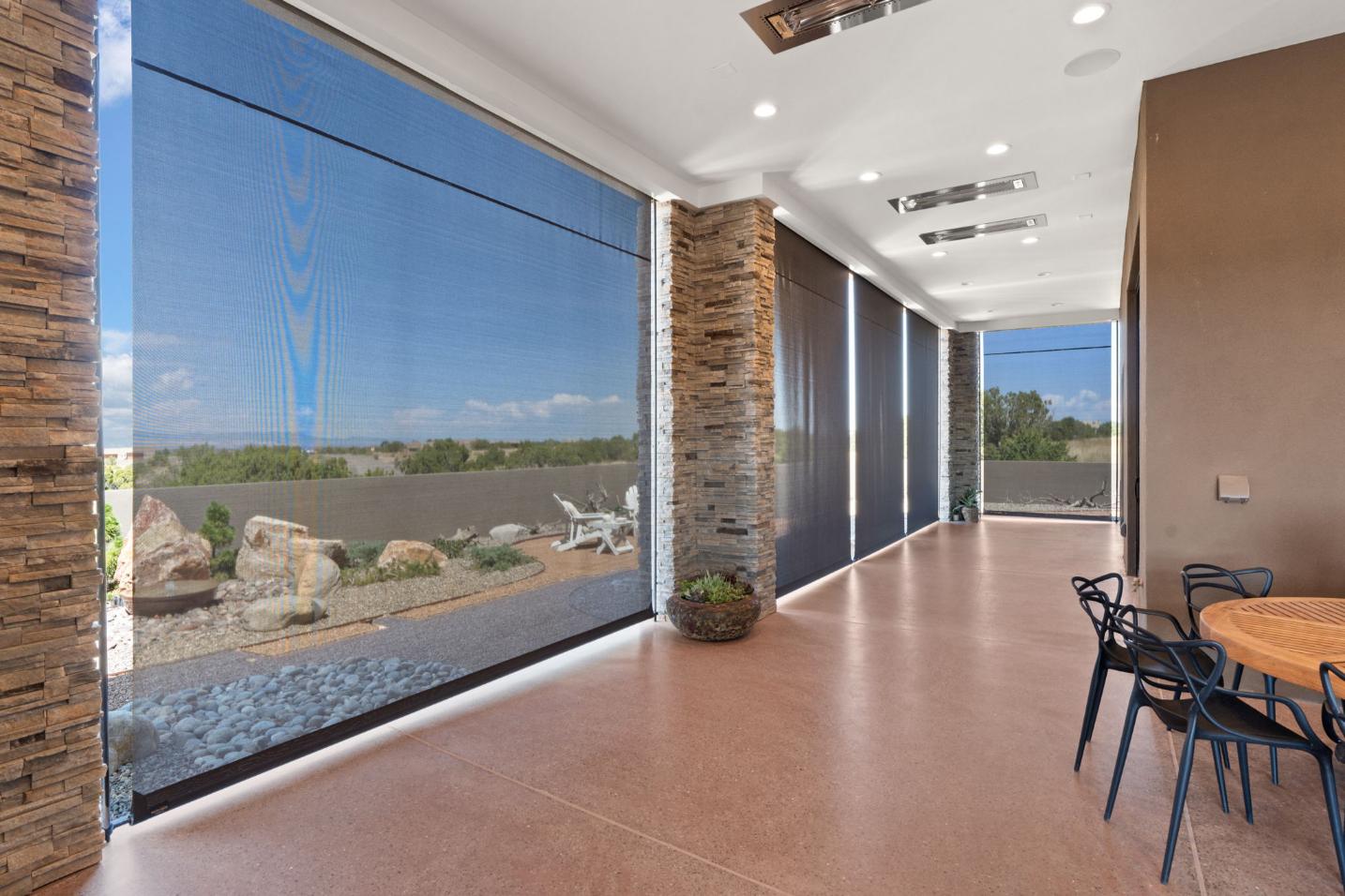 Modern sunroom with large roll-up screens and desert landscape views.