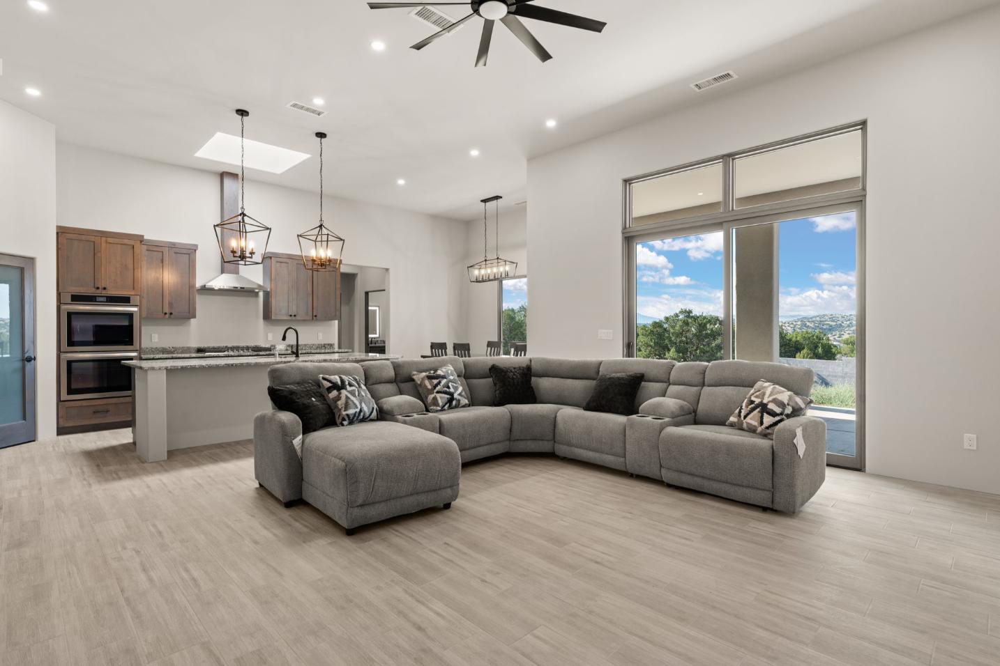 Modern living room with a large gray sectional sofa and open kitchen.