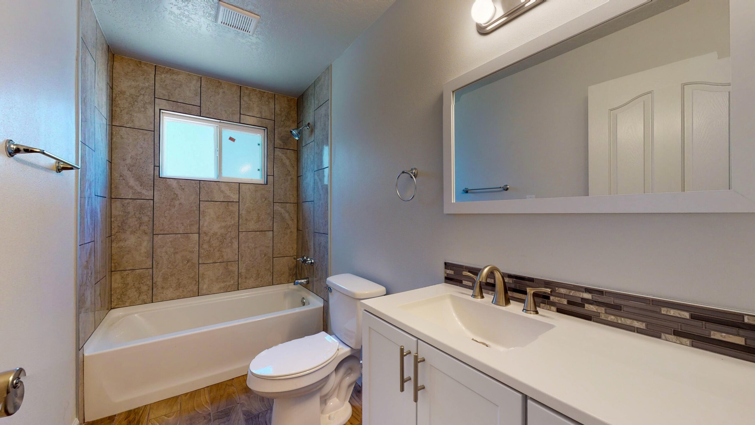 Modern bathroom with bathtub, toilet, and vanity with mirror.