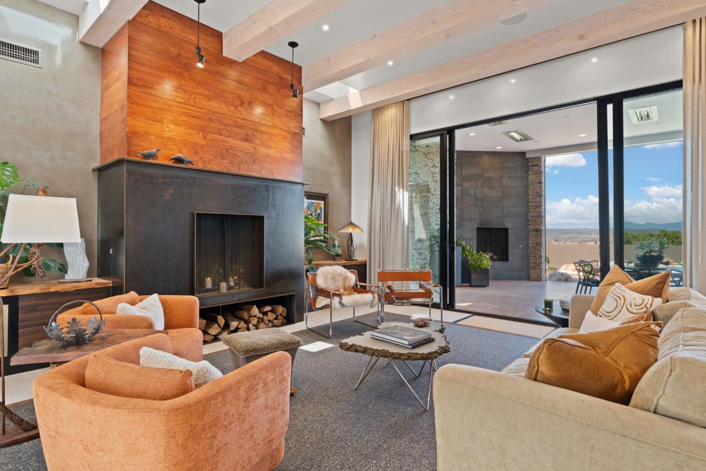 Cozy modern living room with fireplace and large glass doors opening to an outdoor area.