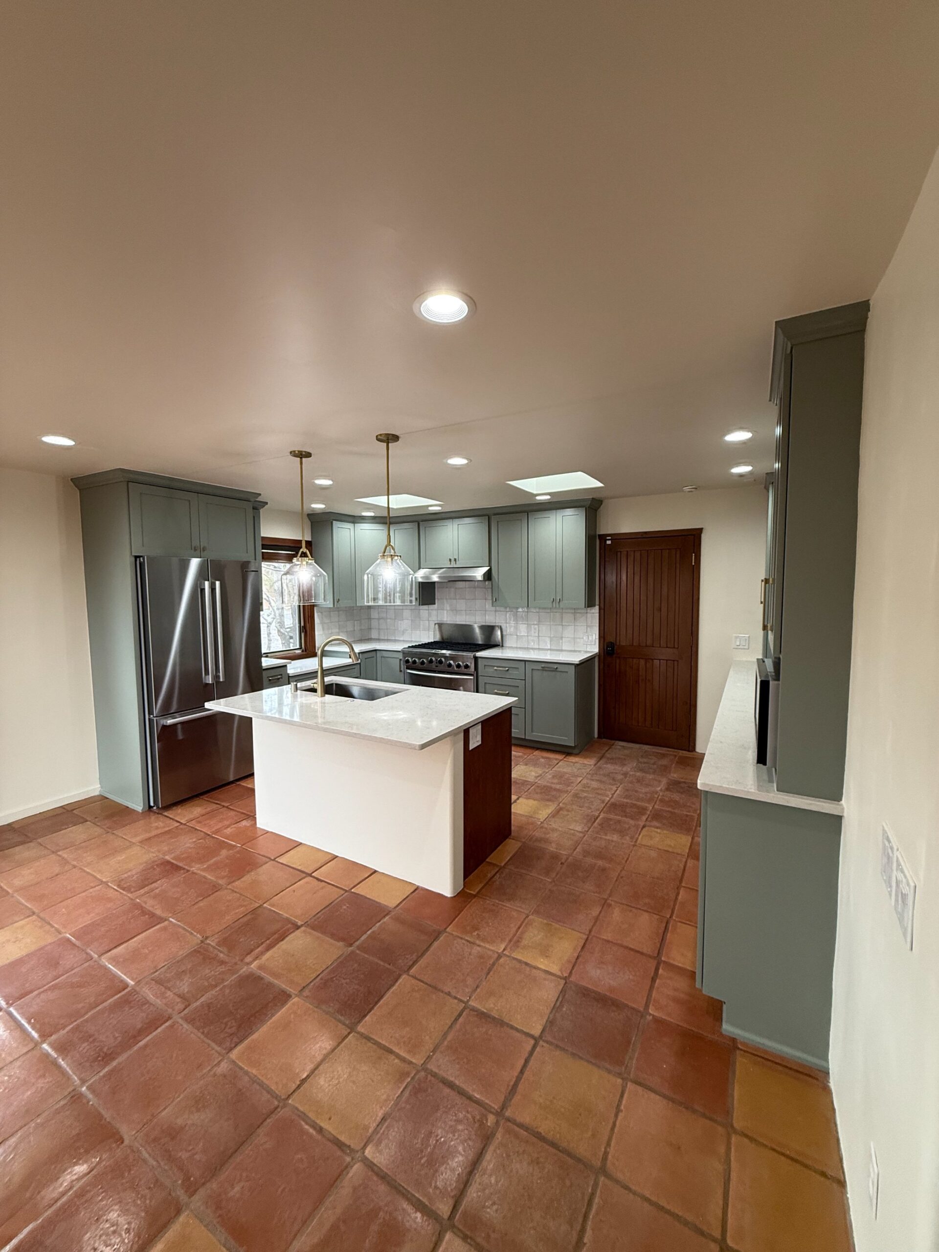 Modern kitchen with white cabinetry and center island under recessed lighting.