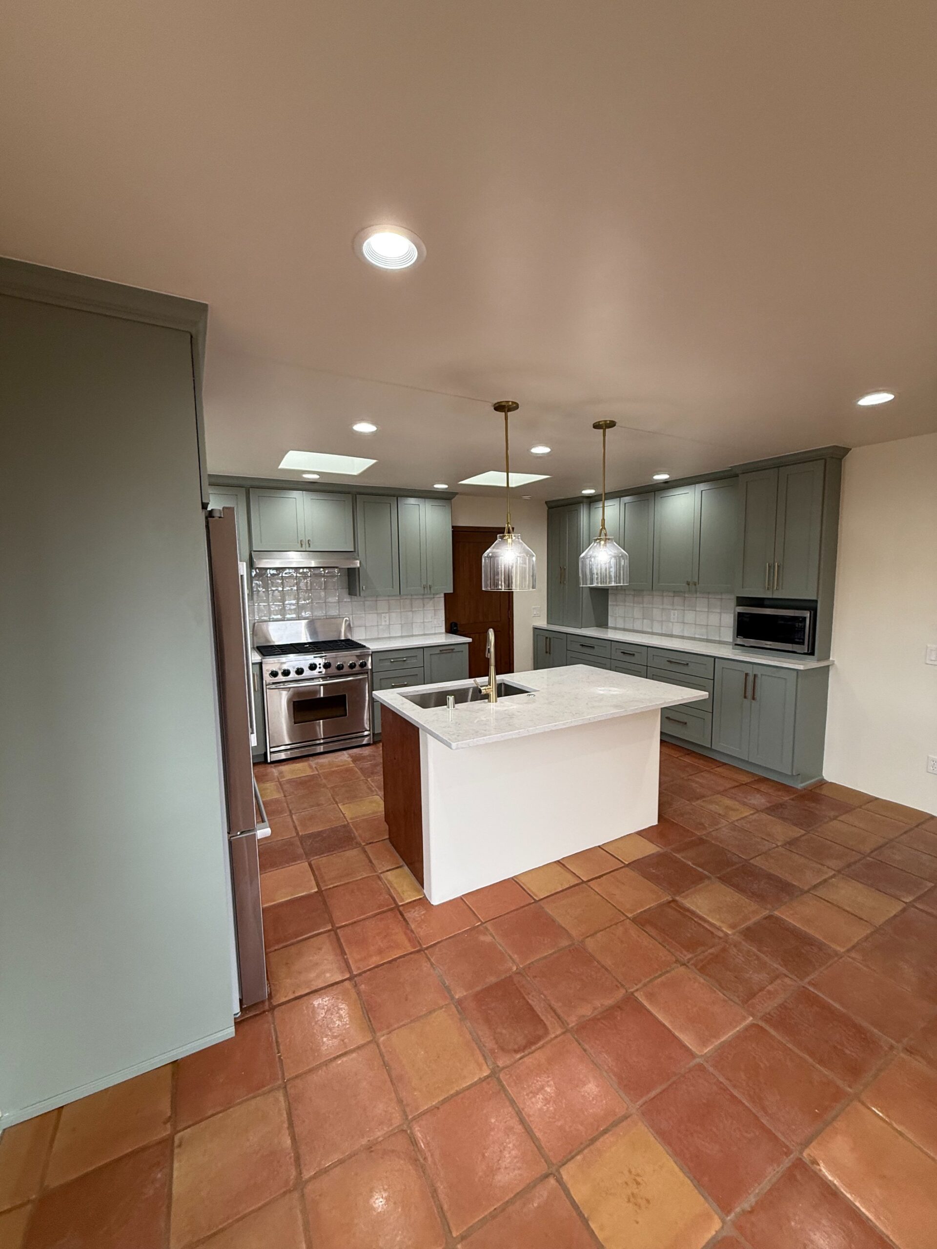 Modern kitchen with white island and gray cabinetry under warm lighting.