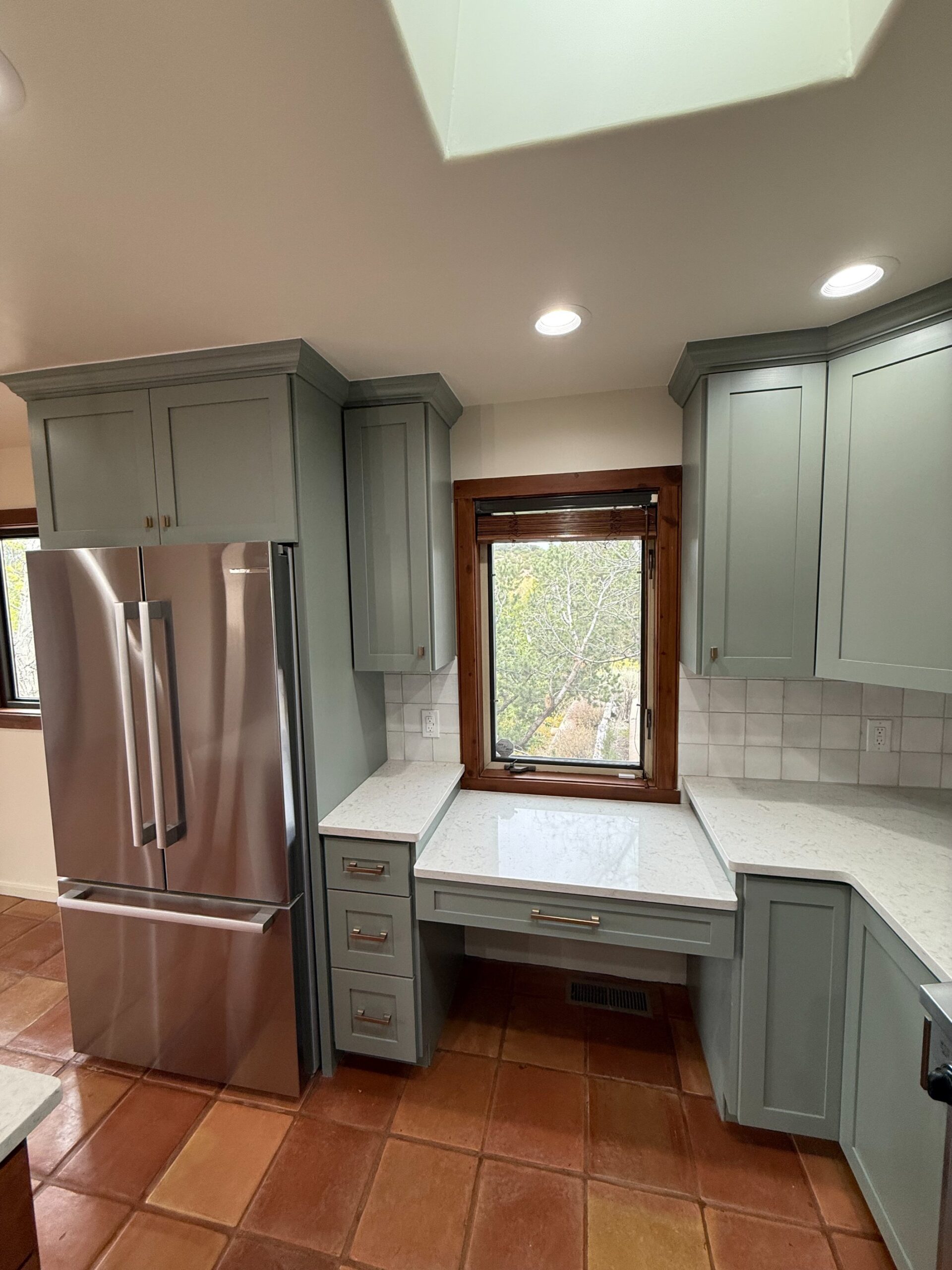 Modern kitchen with gray cabinets and a stainless steel refrigerator.