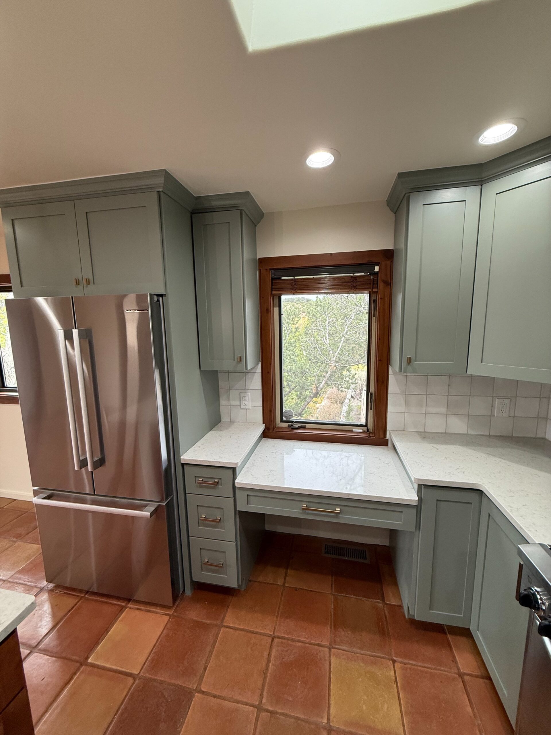 Modern kitchen with gray cabinets and a stainless steel refrigerator.