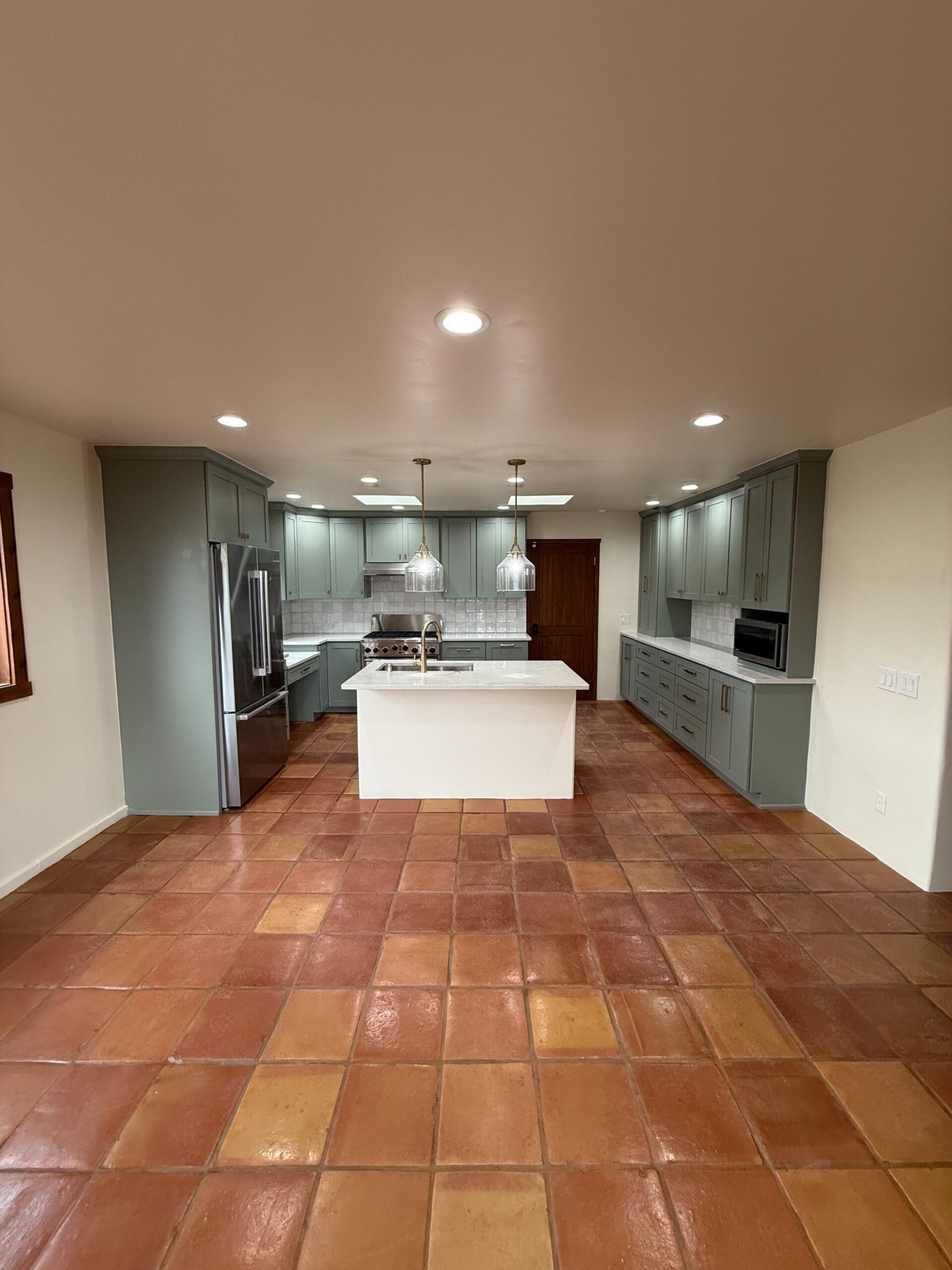 Modern kitchen with central island and tiled floor.