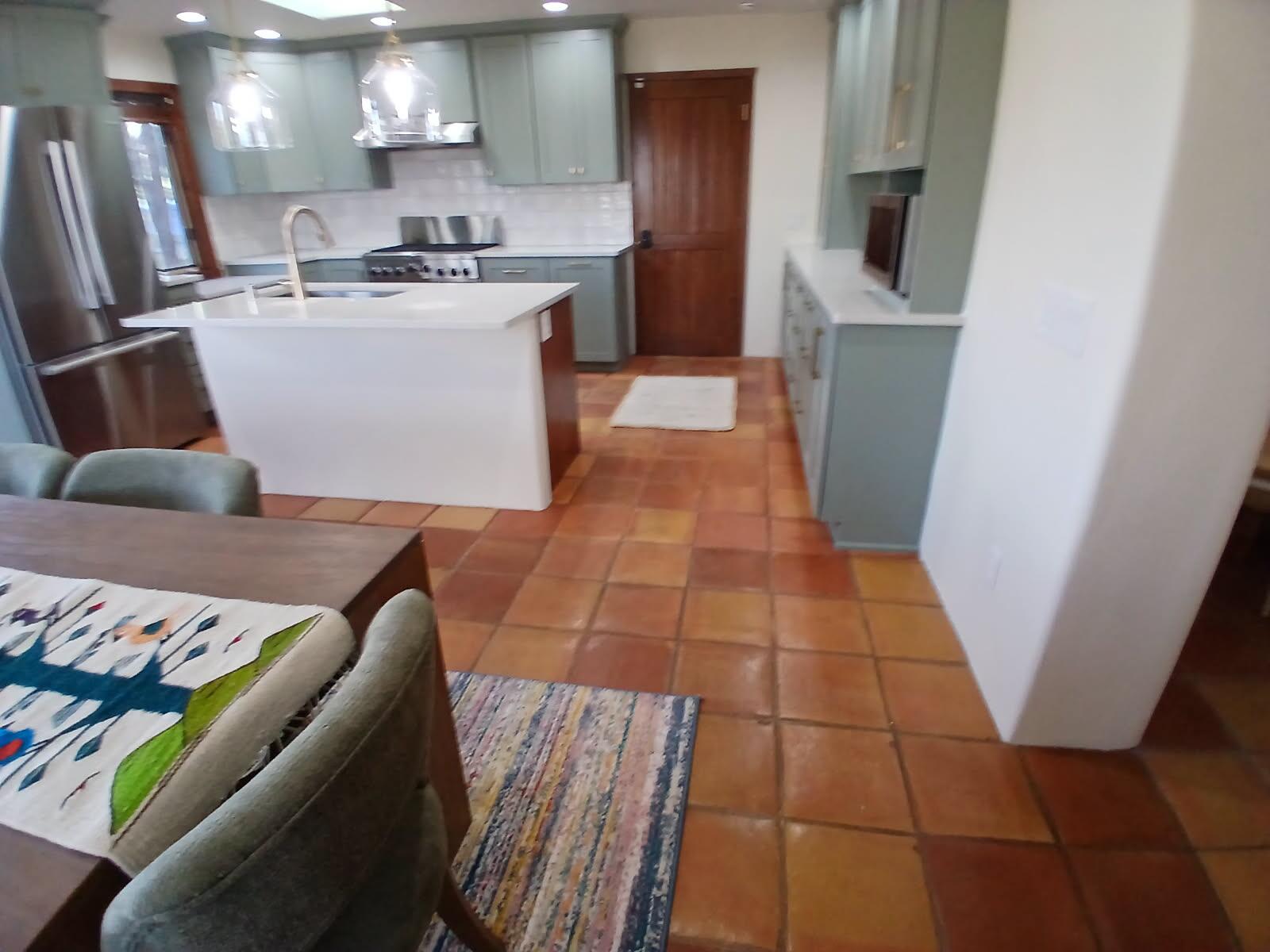Cozy kitchen with terracotta tile flooring and modern white cabinetry.