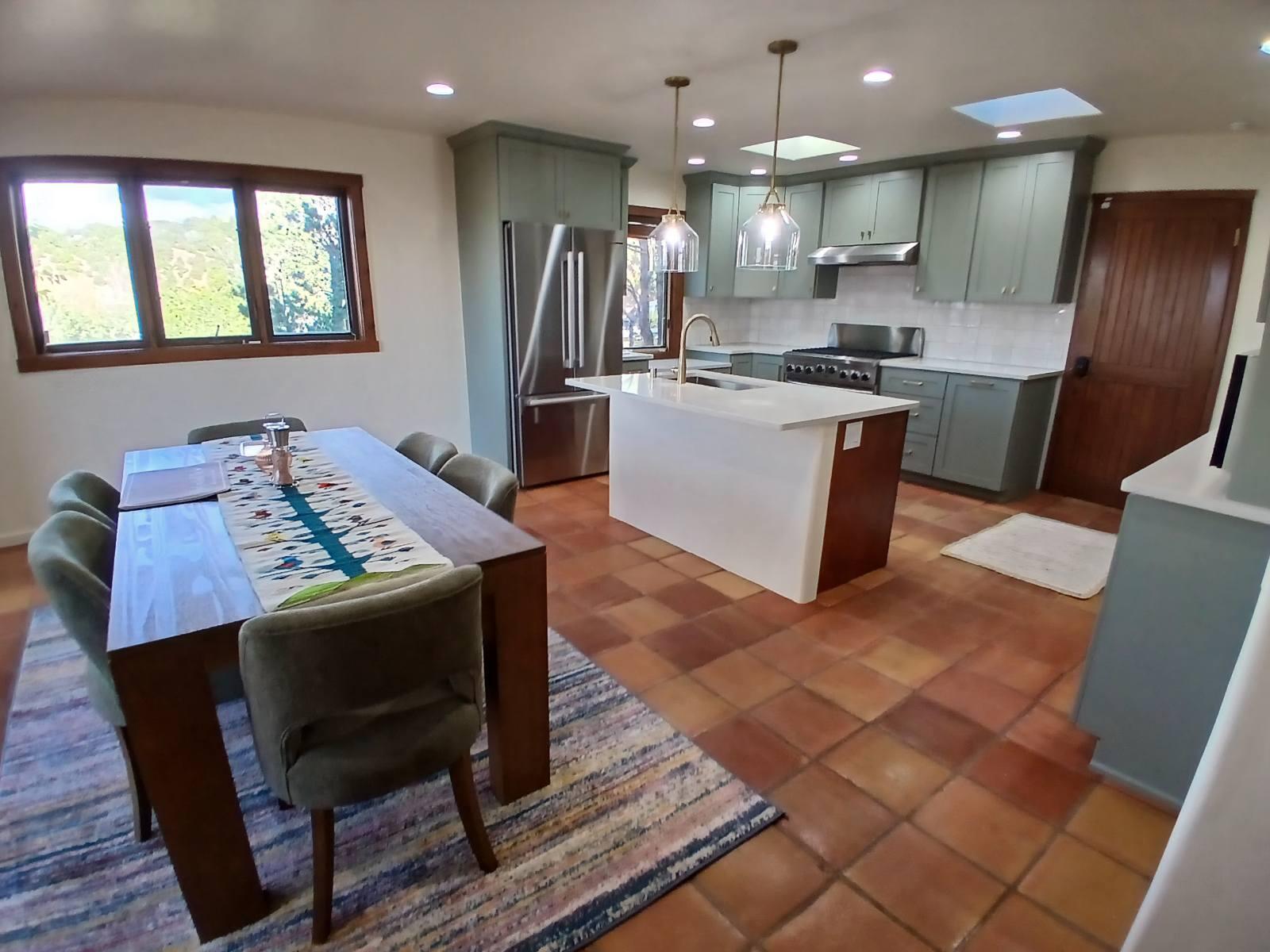 Modern kitchen with island, stainless steel appliances, and dining table.