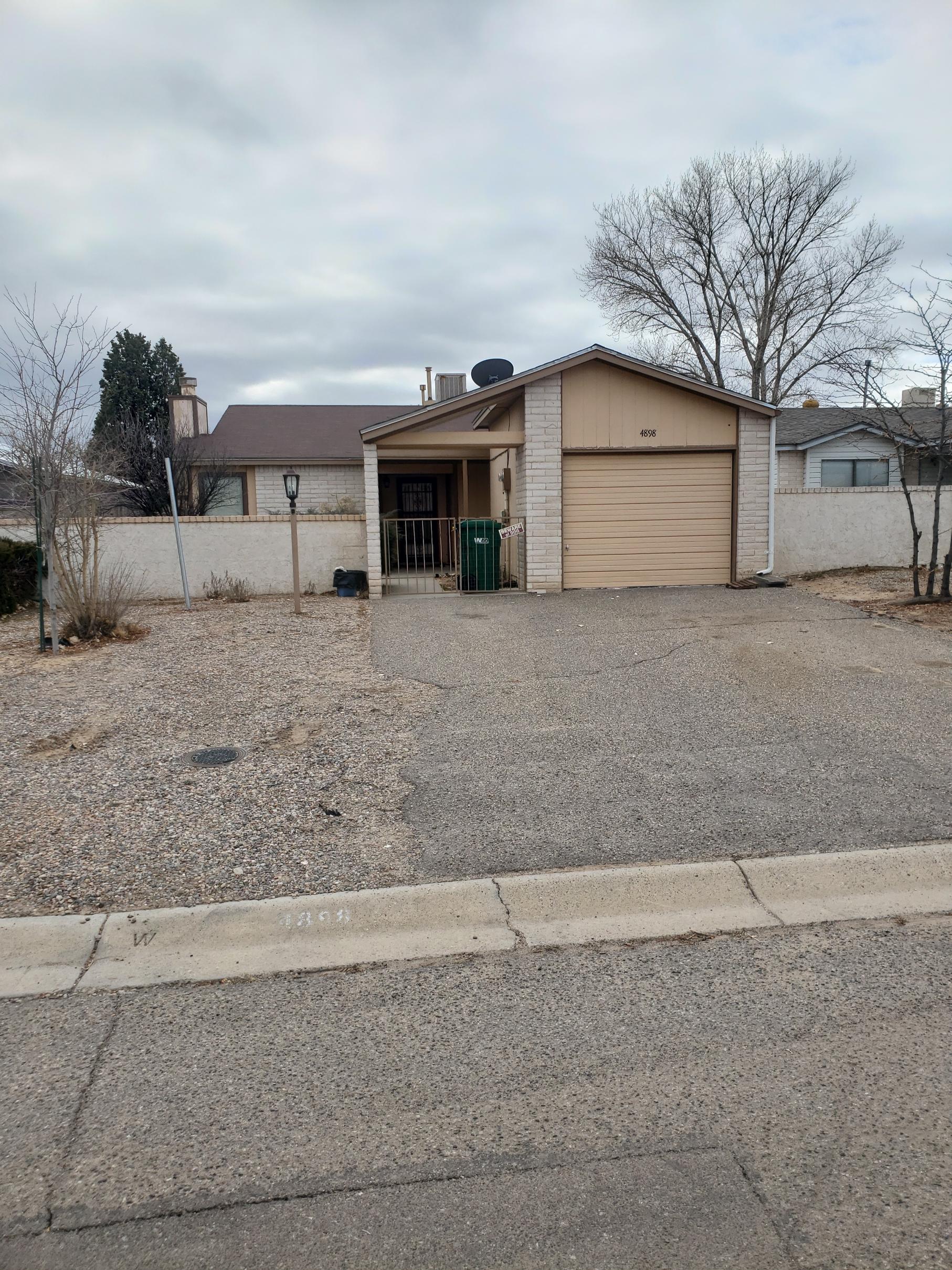 Single-story house with a gravel driveway and a garage under cloudy sky.