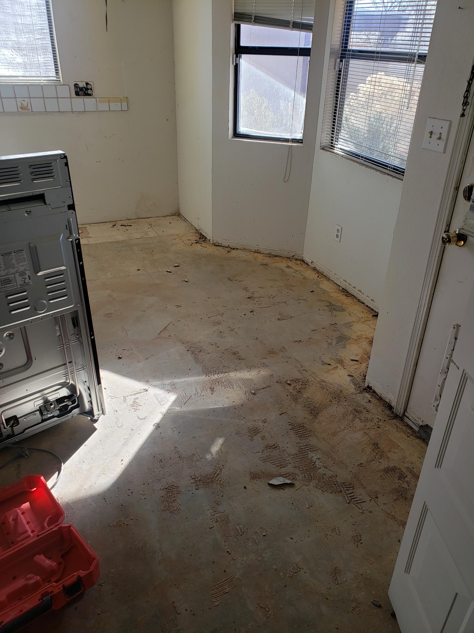 Empty room with stained floor and a large appliance.