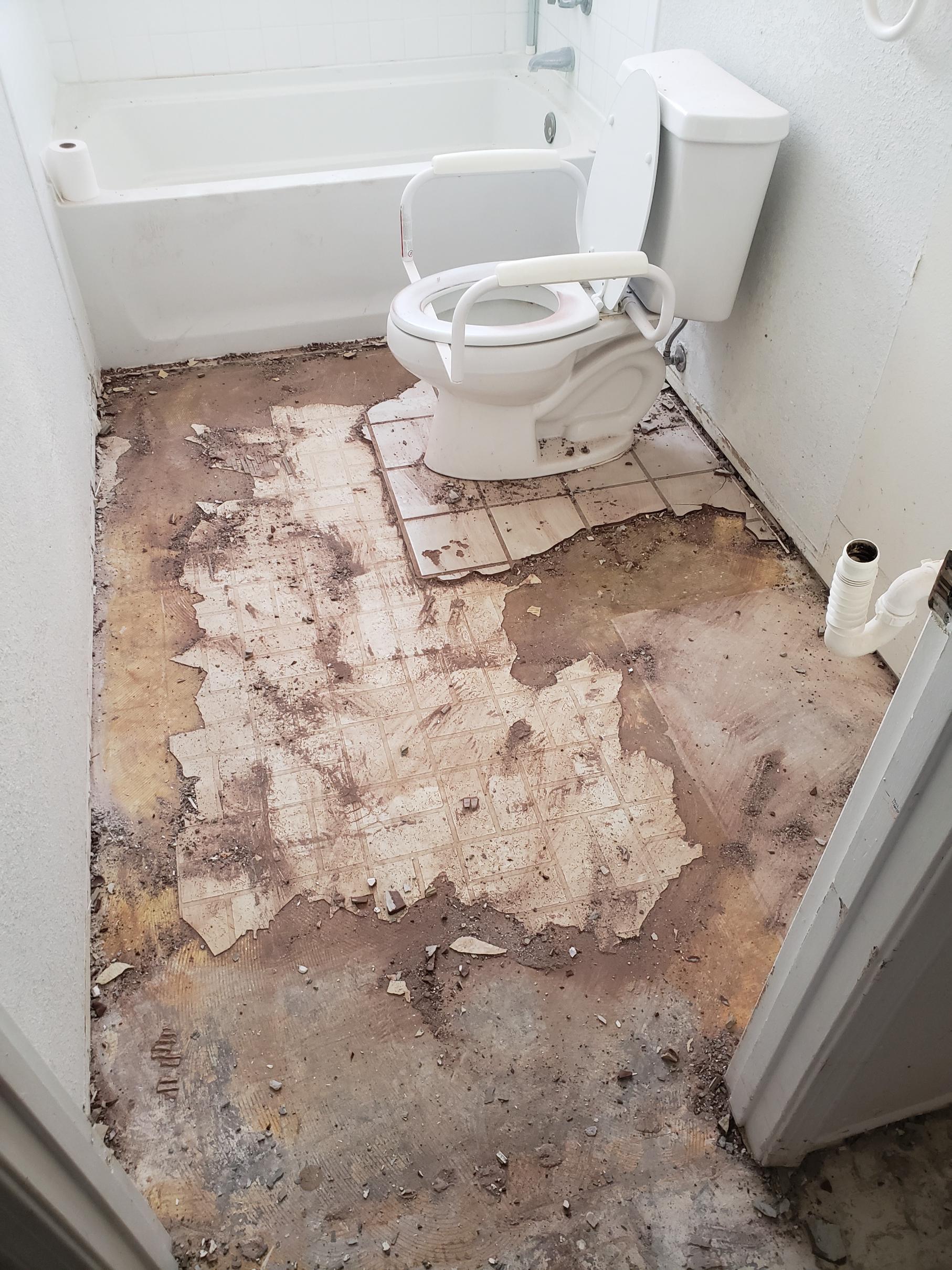 Old toilet on a bare, stained bathroom floor.