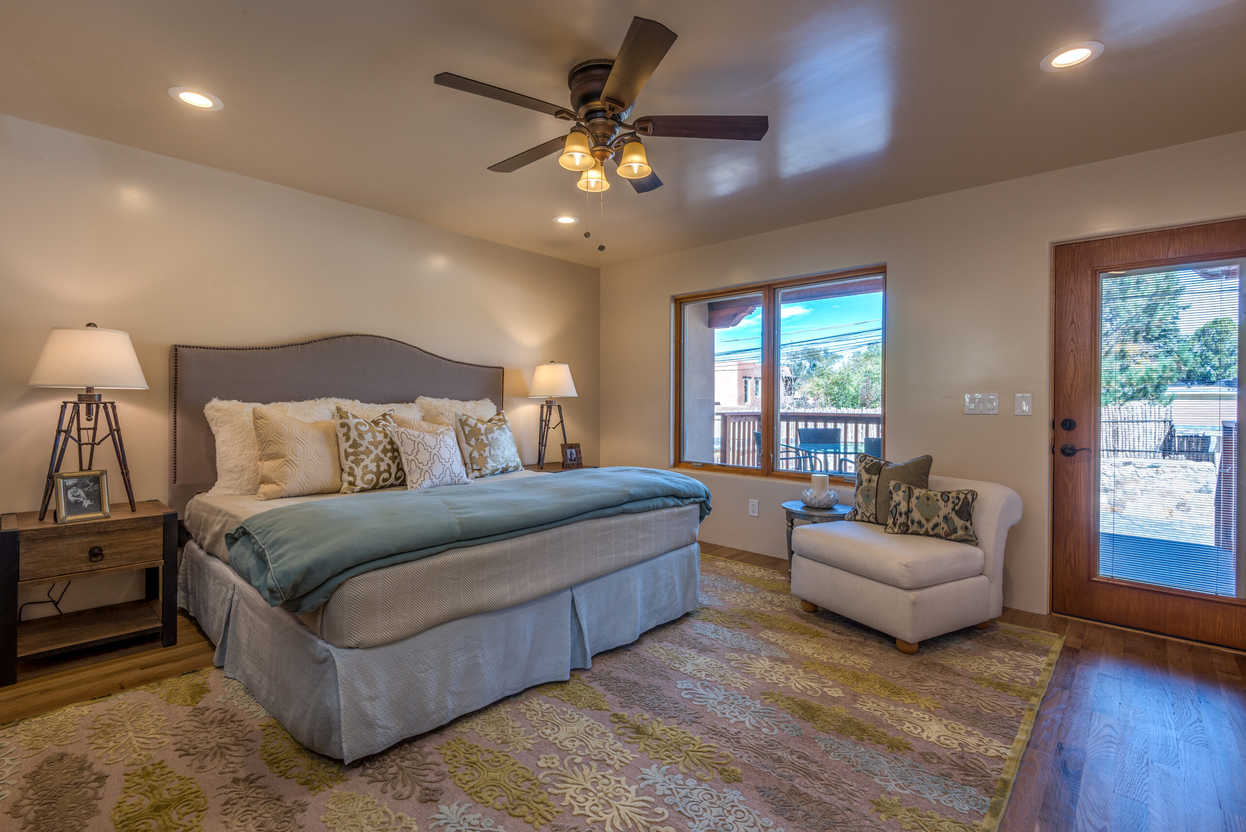Cozy bedroom with a large bed, armchair, and ceiling fan.