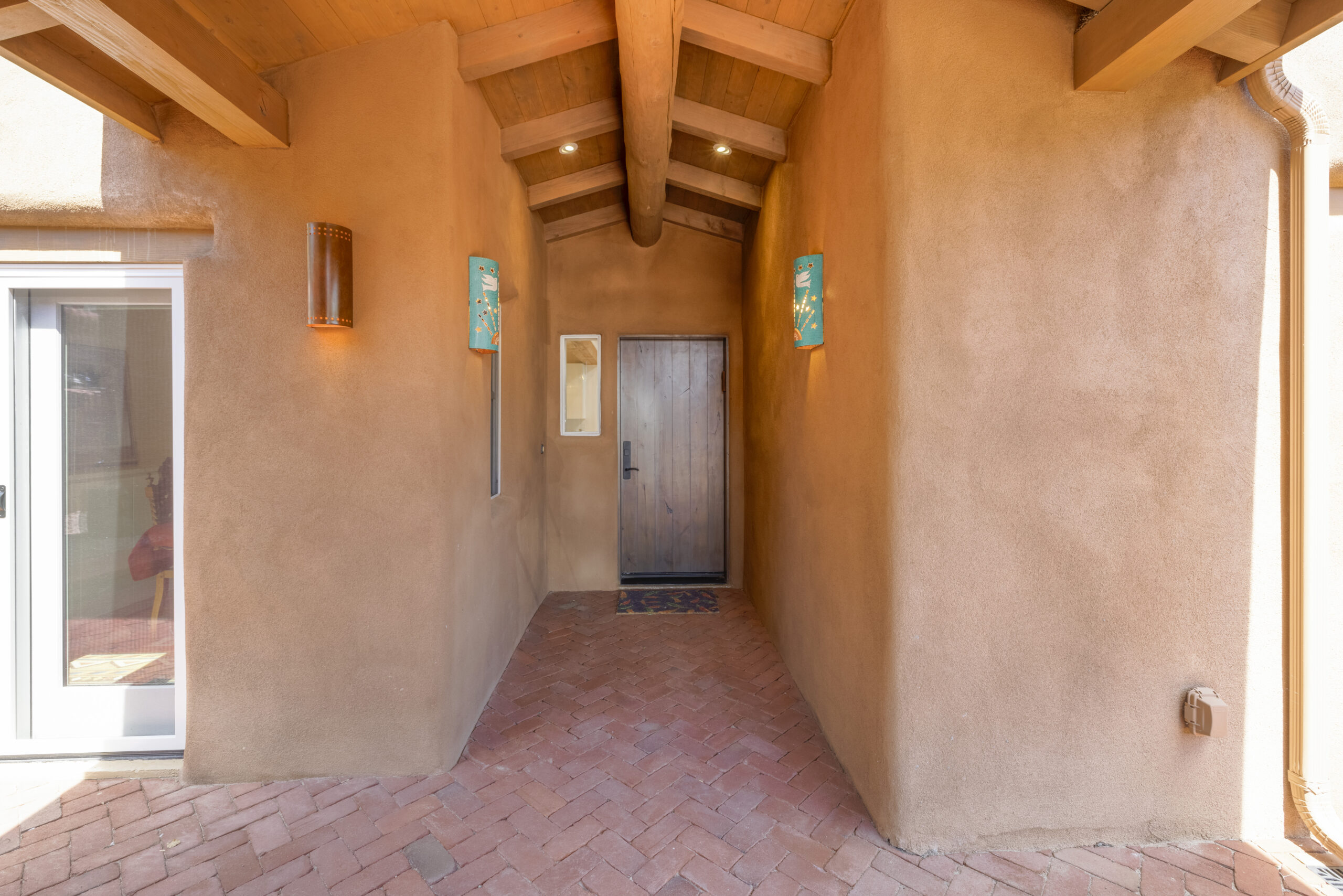 A rustic hallway with wooden door and adobe walls.
