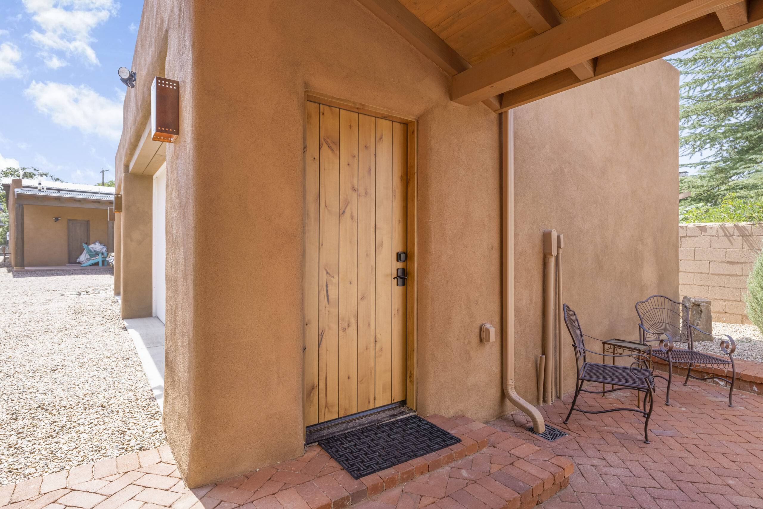 Wooden door on a rustic adobe wall with a black doormat.