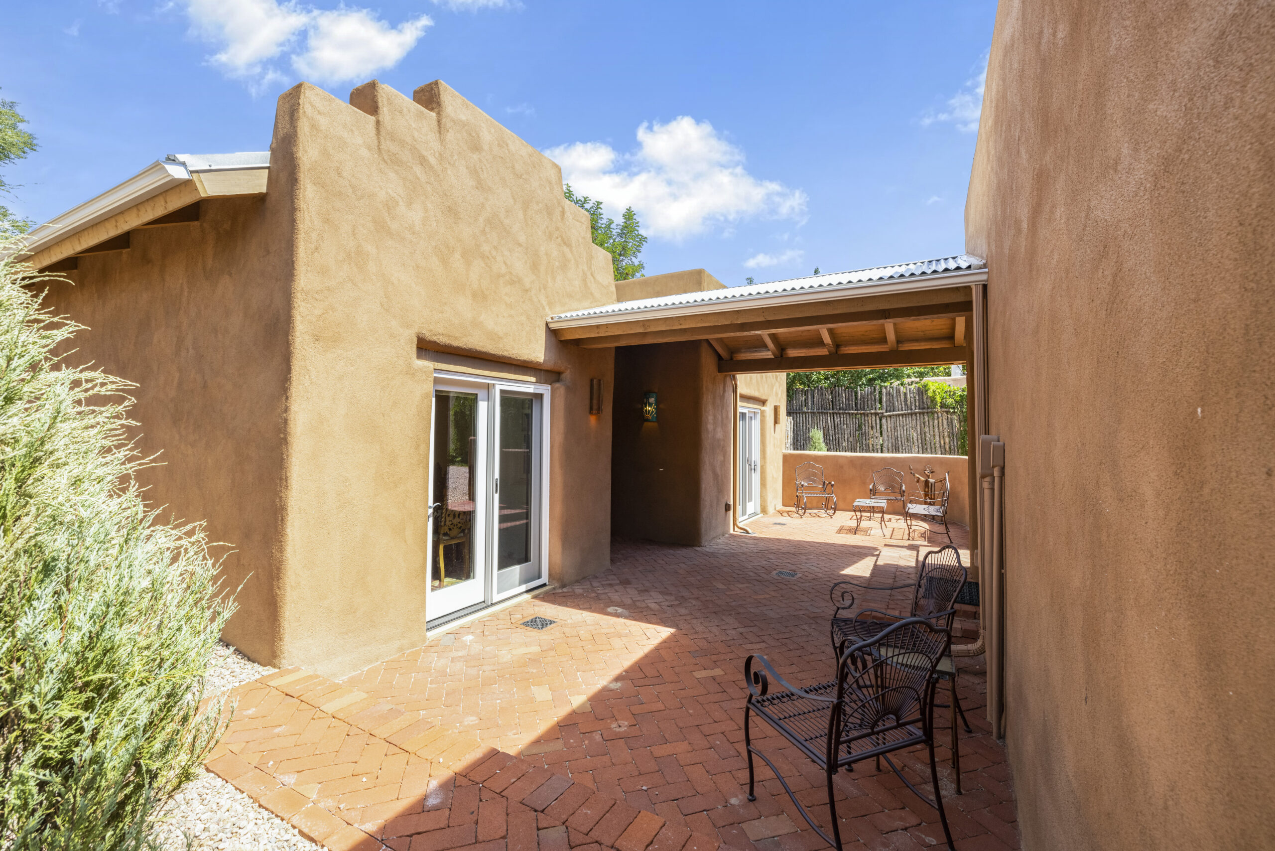 Sunny adobe patio with rustic outdoor seating under a clear blue sky.