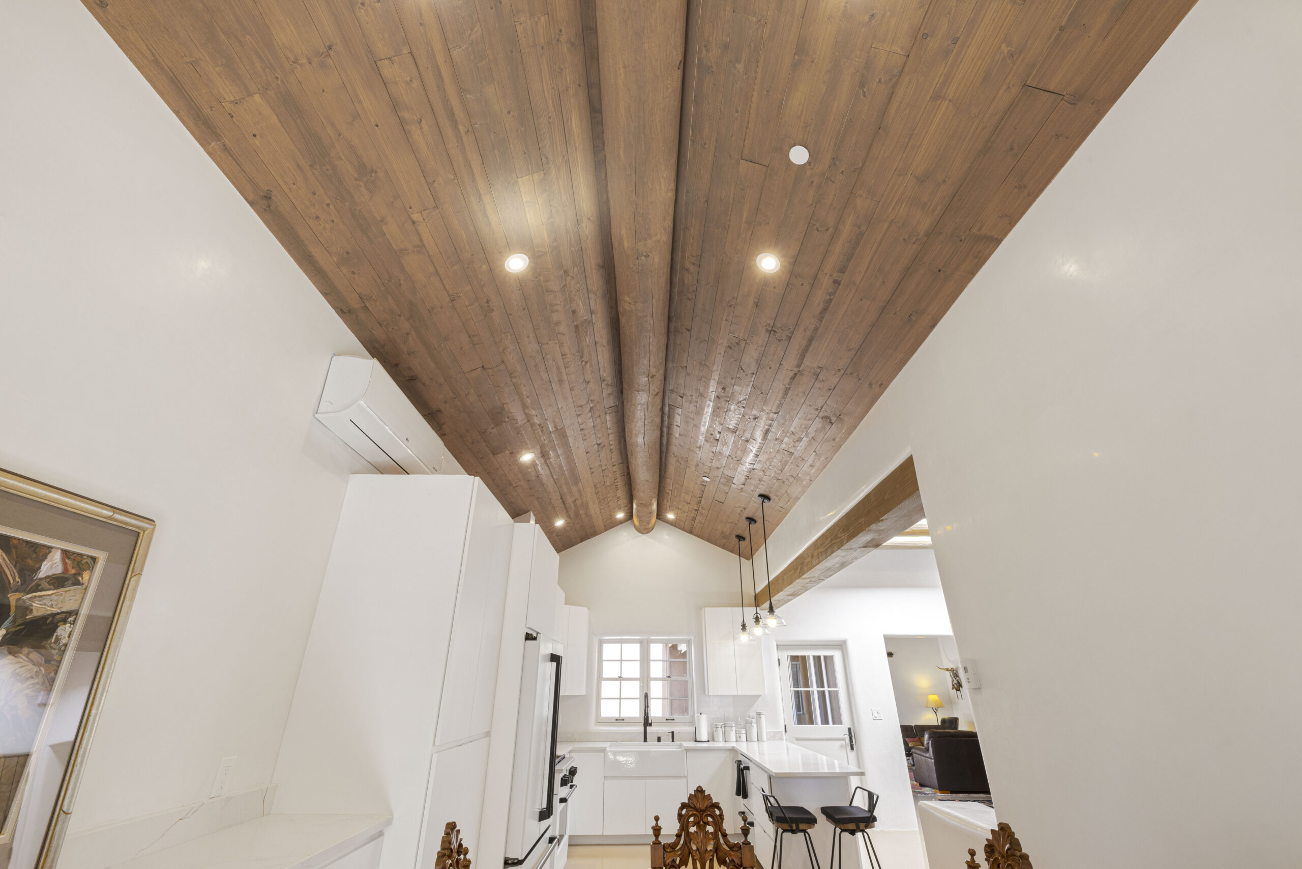 Spacious modern living area with wooden ceiling and white walls.