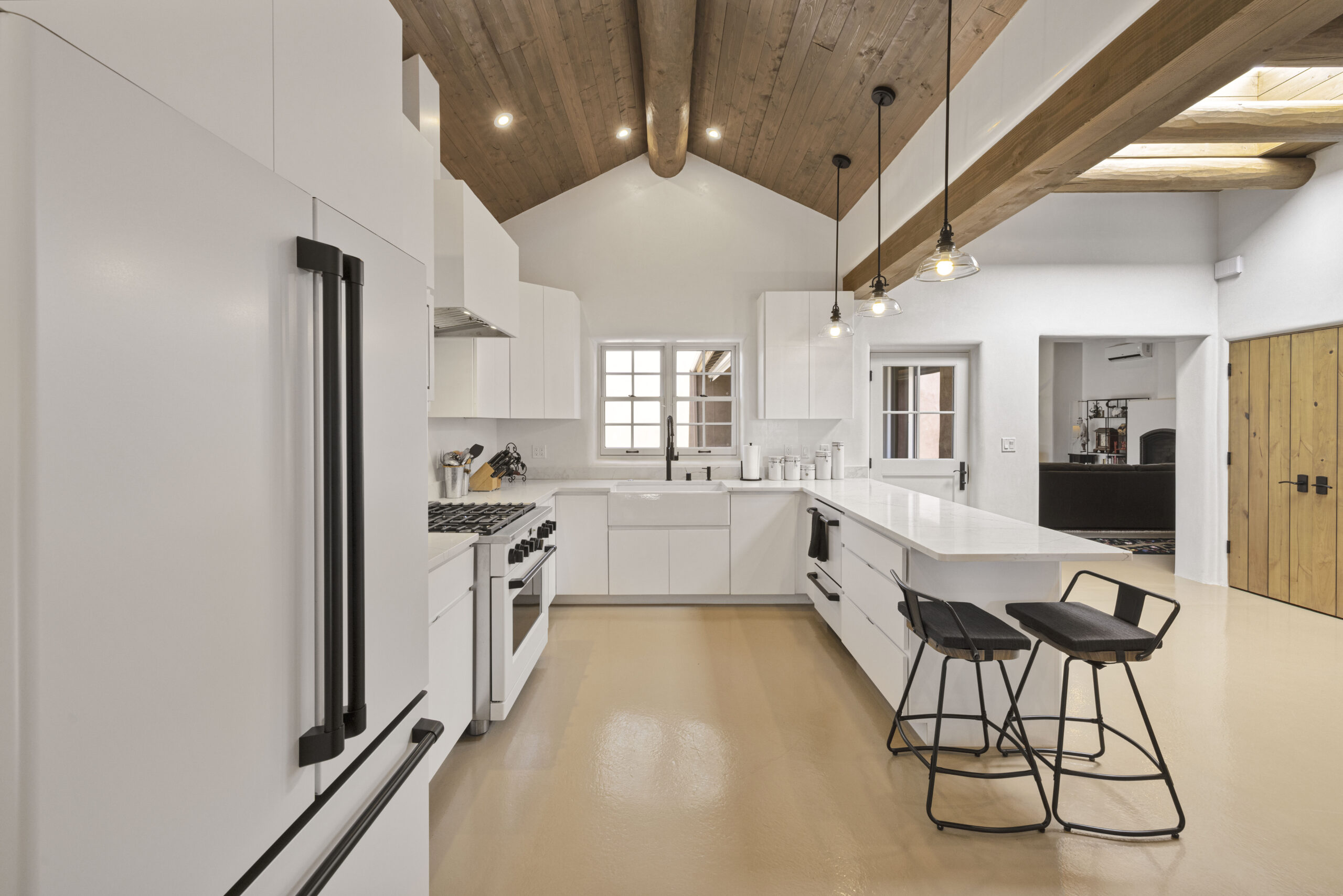 Modern kitchen with wooden ceiling beams and white cabinetry.