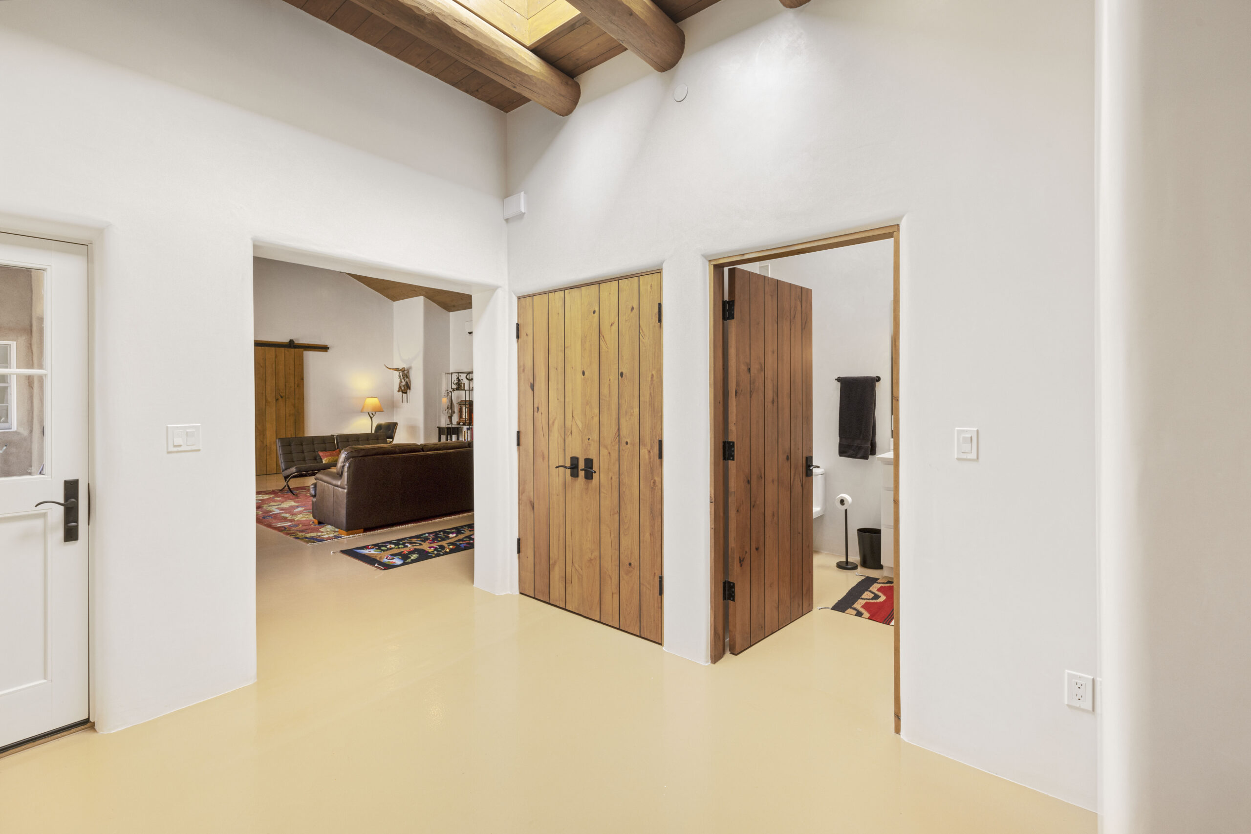 Modern interior with wooden doors and exposed ceiling beams.