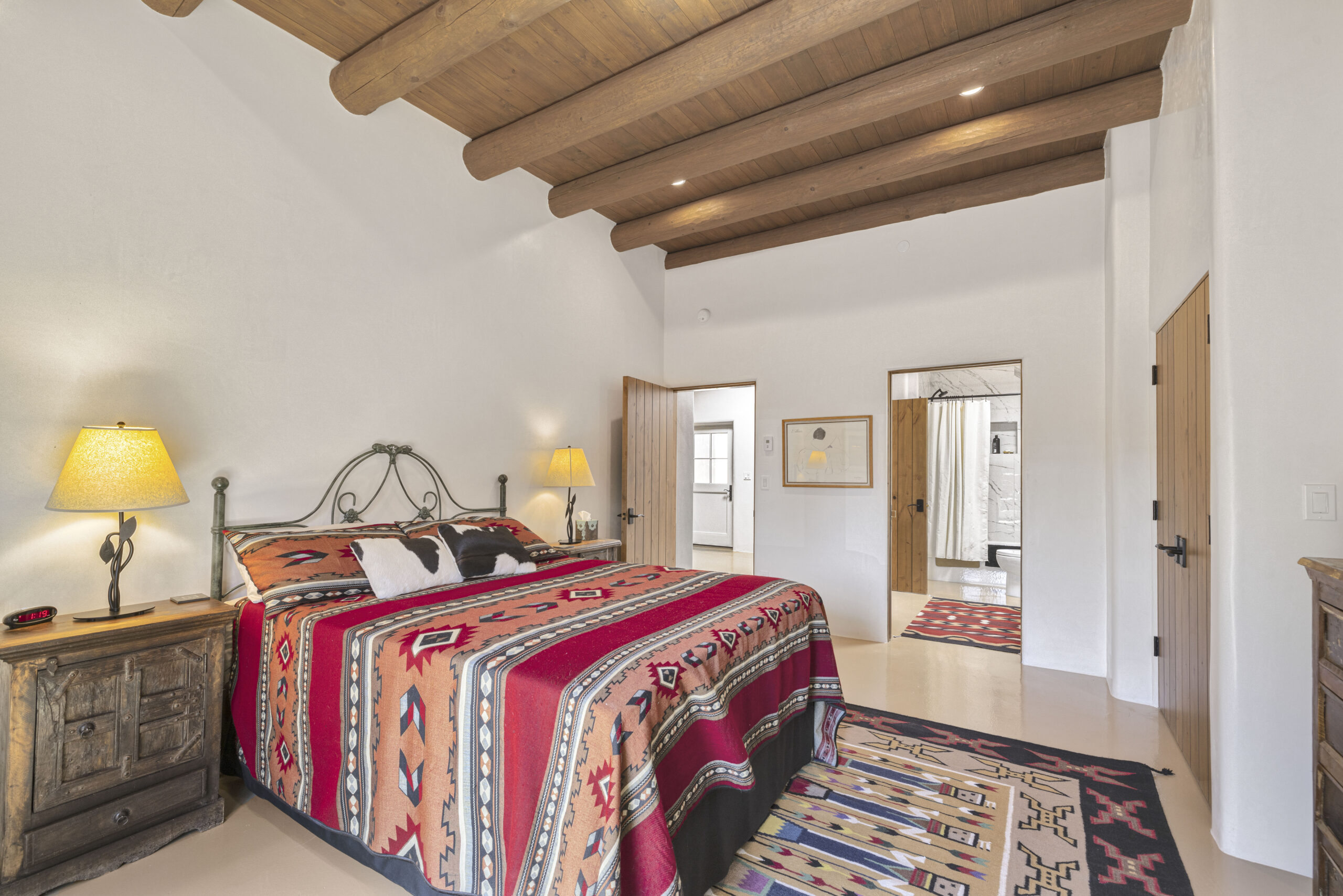 Cozy bedroom with colorful bedding and wooden ceiling beams.