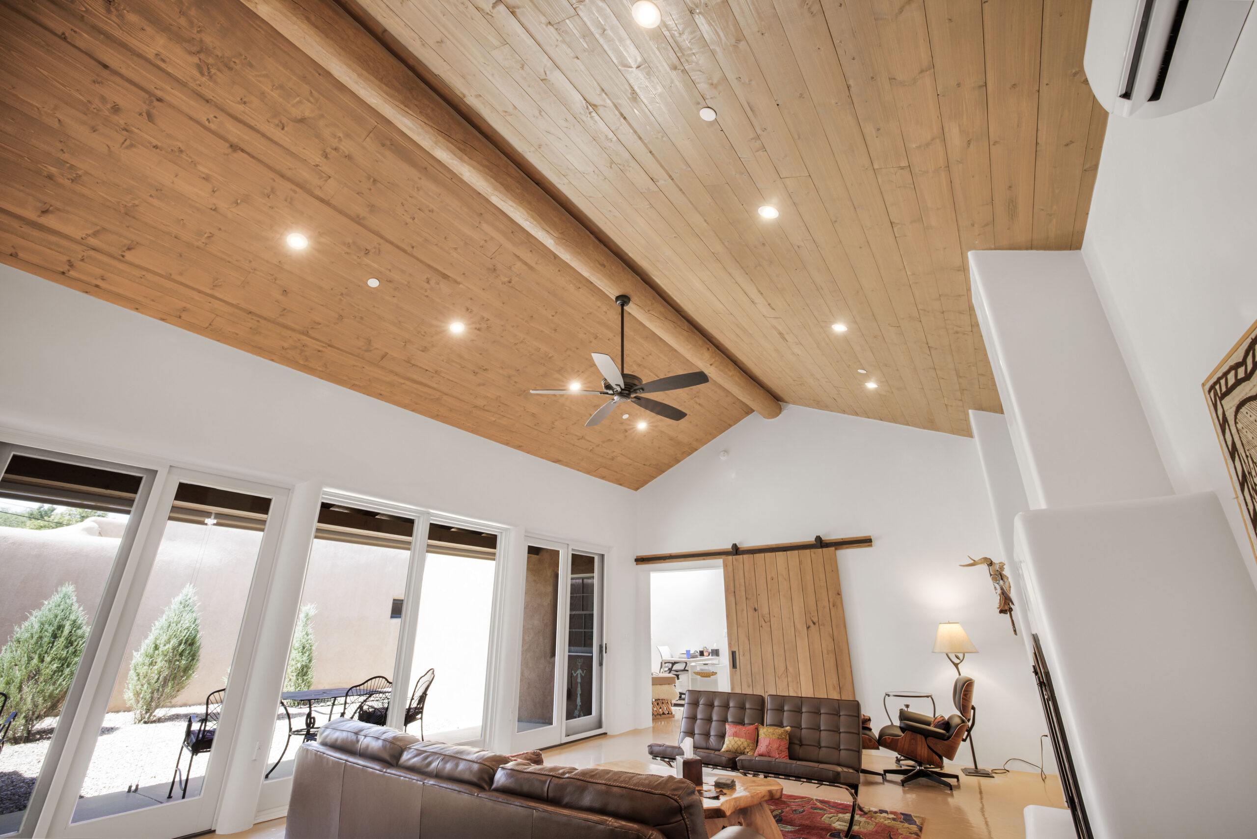 Spacious living room with vaulted wooden ceiling and large windows.