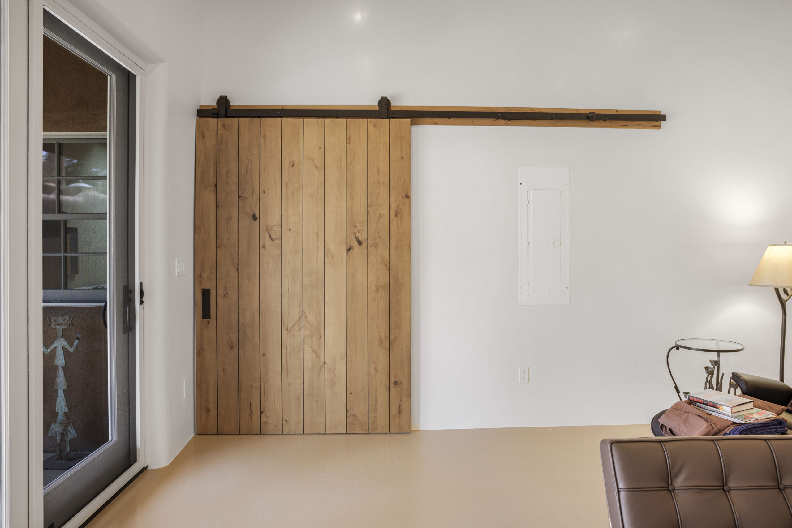 Modern rustic sliding wooden barn door on a white wall.