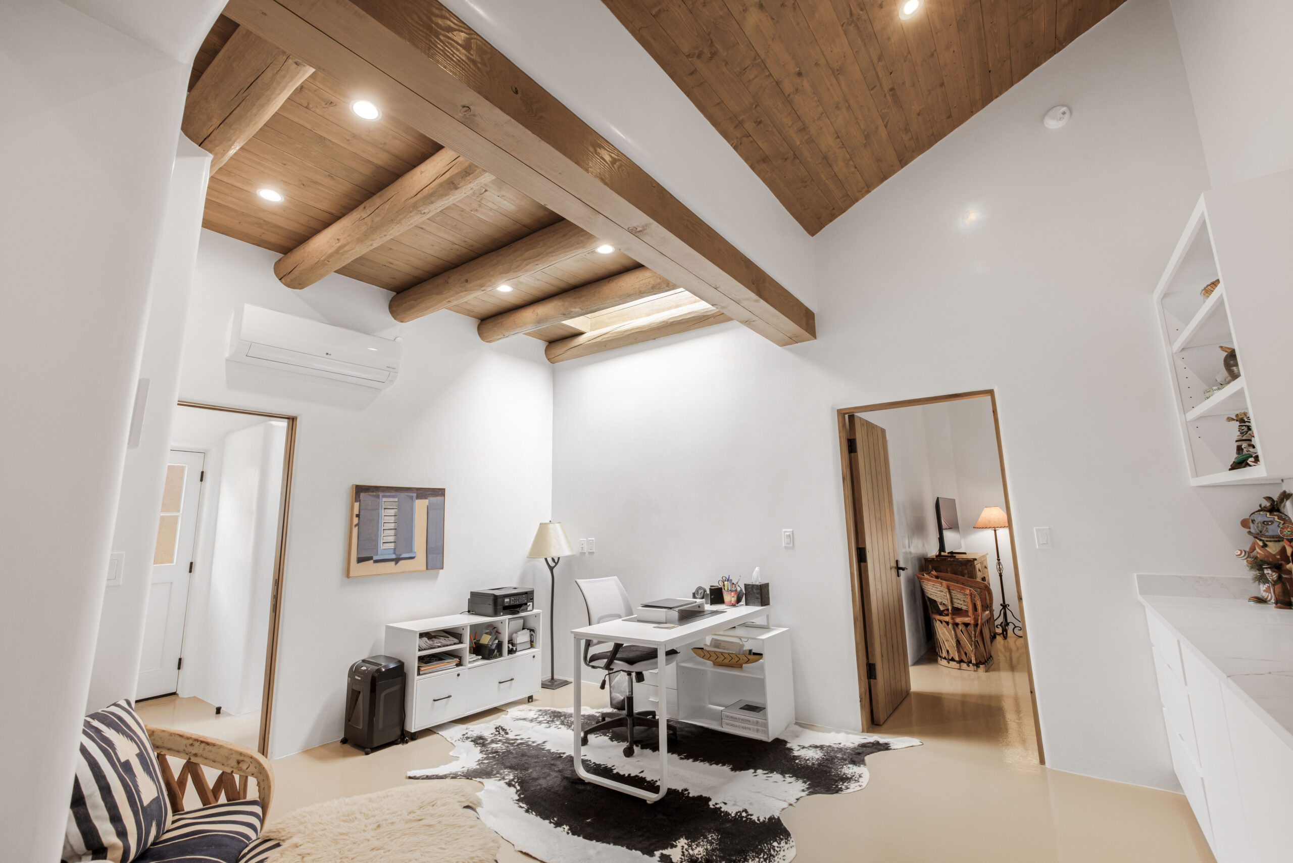 Bright room with wooden beams and cowhide rug.