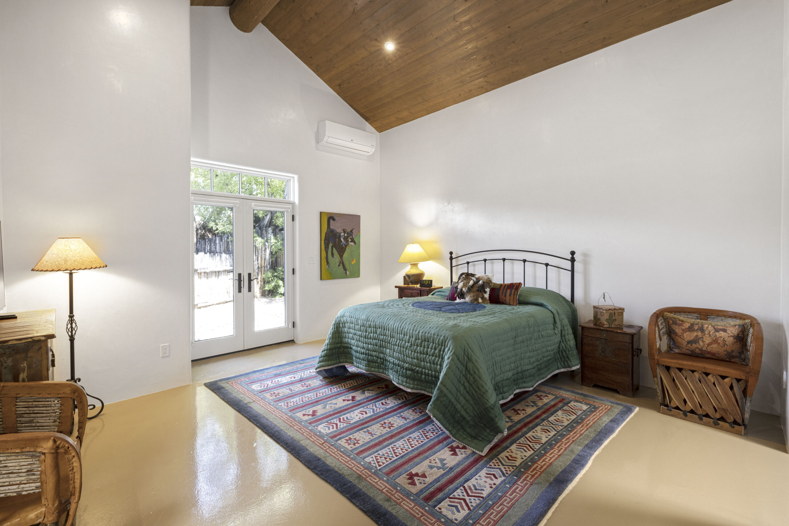 Cozy bedroom with wooden ceiling and green bedding.