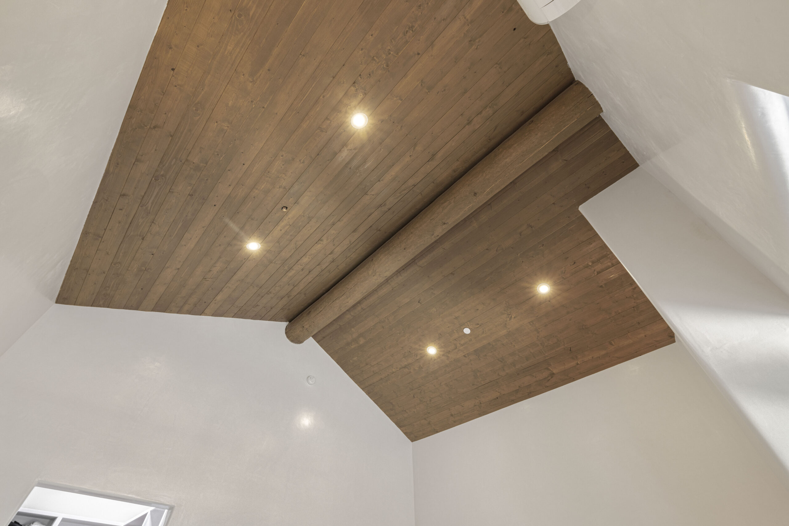 Modern ceiling with wooden panels and recessed lights.