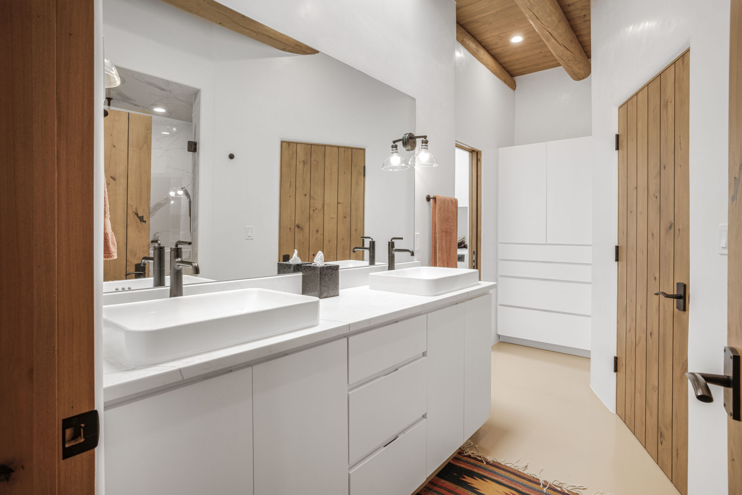 Modern bathroom with double sinks and wooden accents.