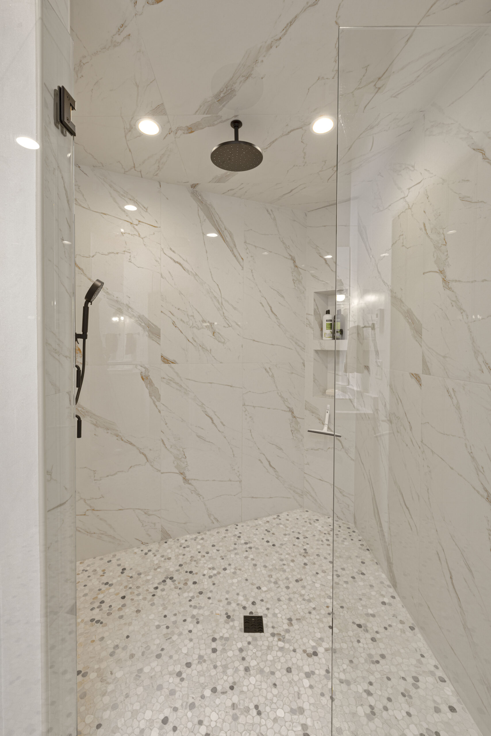 Modern walk-in shower with marble walls and terrazzo floor.