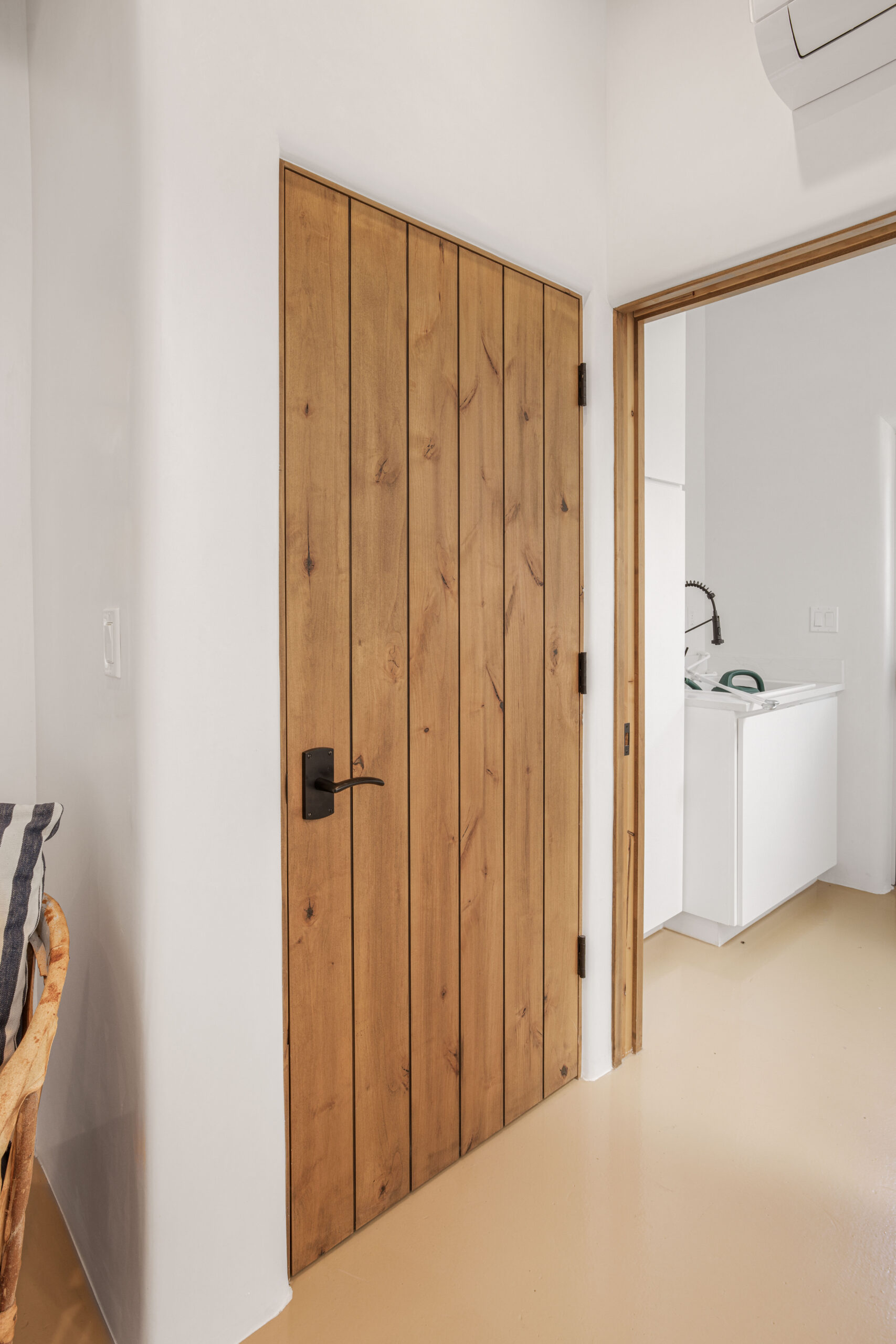 Wooden door with black handle in a minimalist interior.