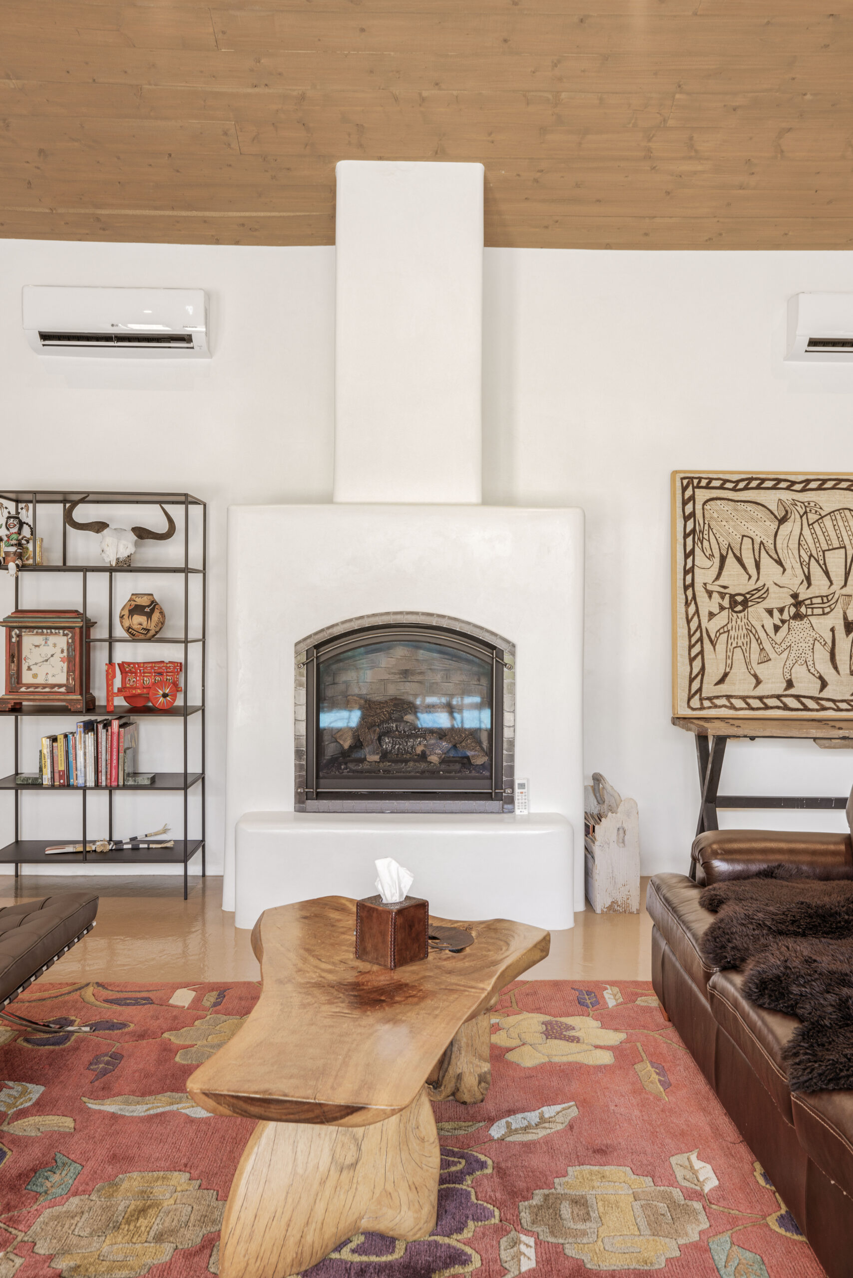 Cozy living room with a fireplace, rustic shelves, and colorful rugs.