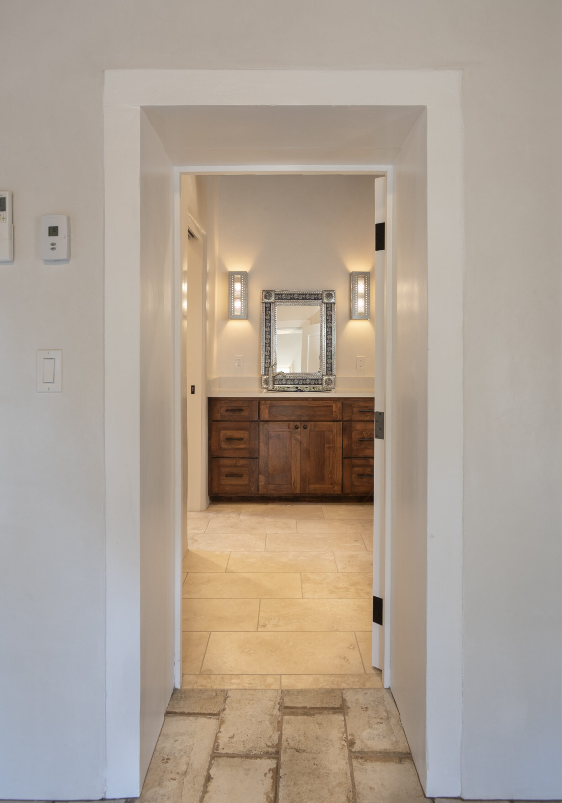 Elegant hallway leading to a bathroom with a wooden vanity and framed mirror.