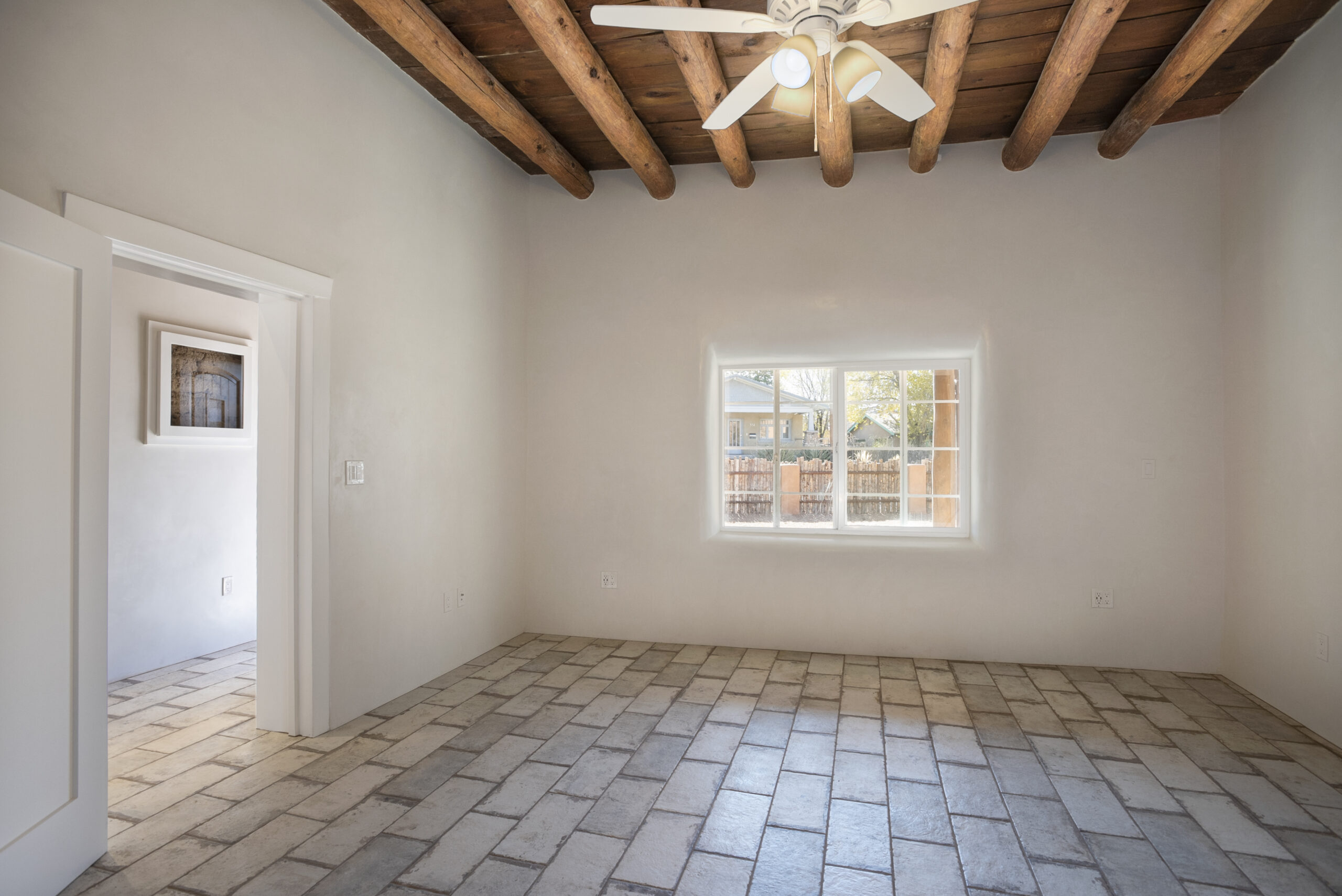 Empty room with rustic ceiling beams and a tiled floor.