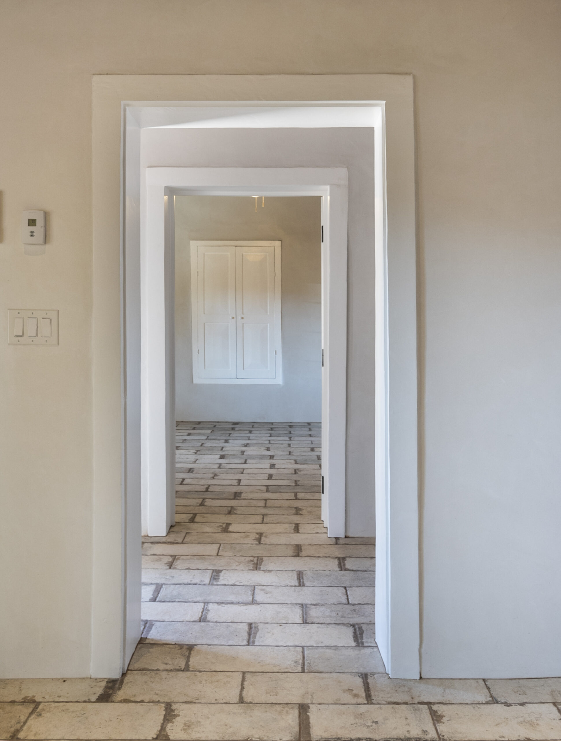 A series of white doorways aligned in a row with tiled floors.
