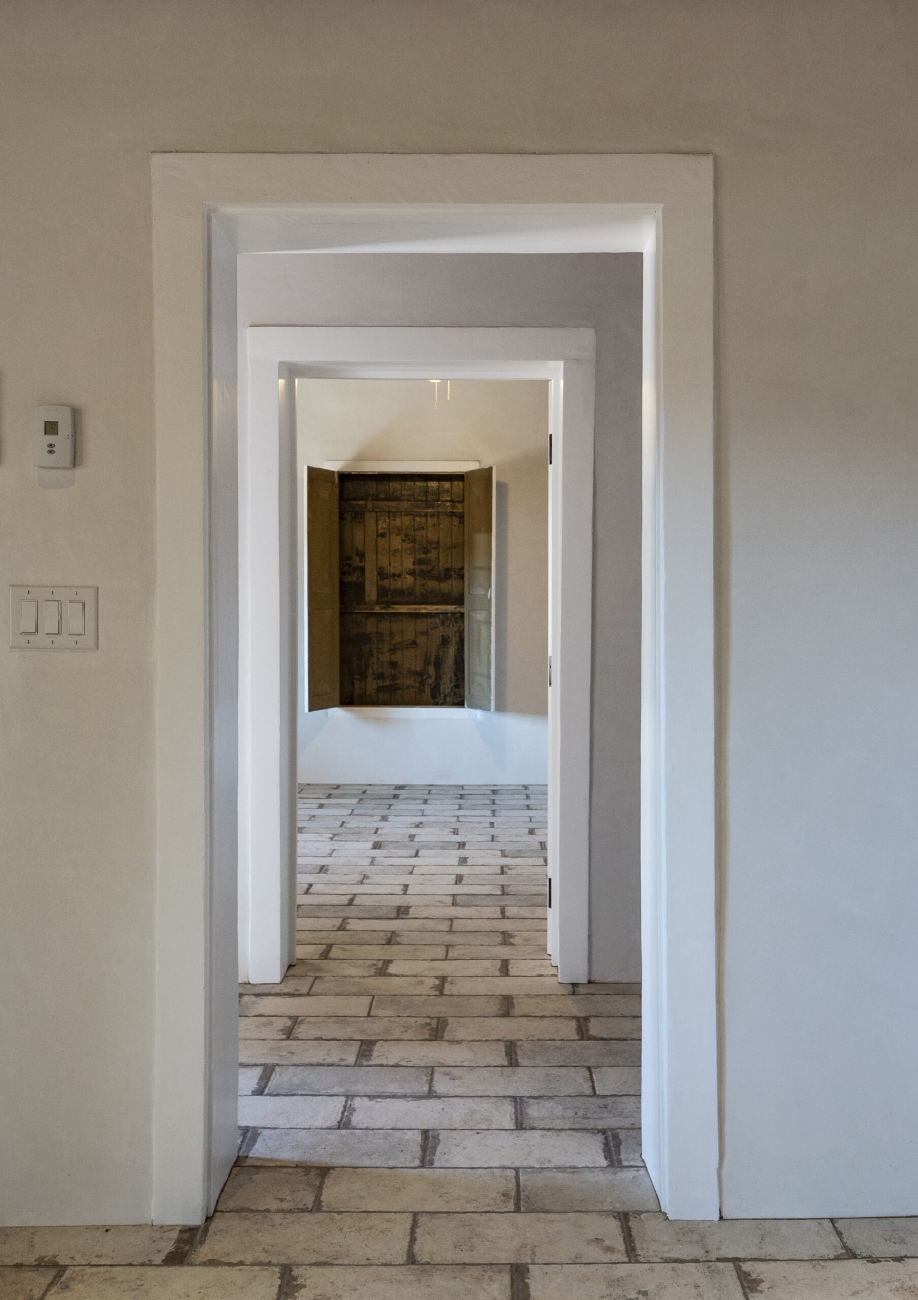 View through aligned doorways into a room with patterned tile flooring.