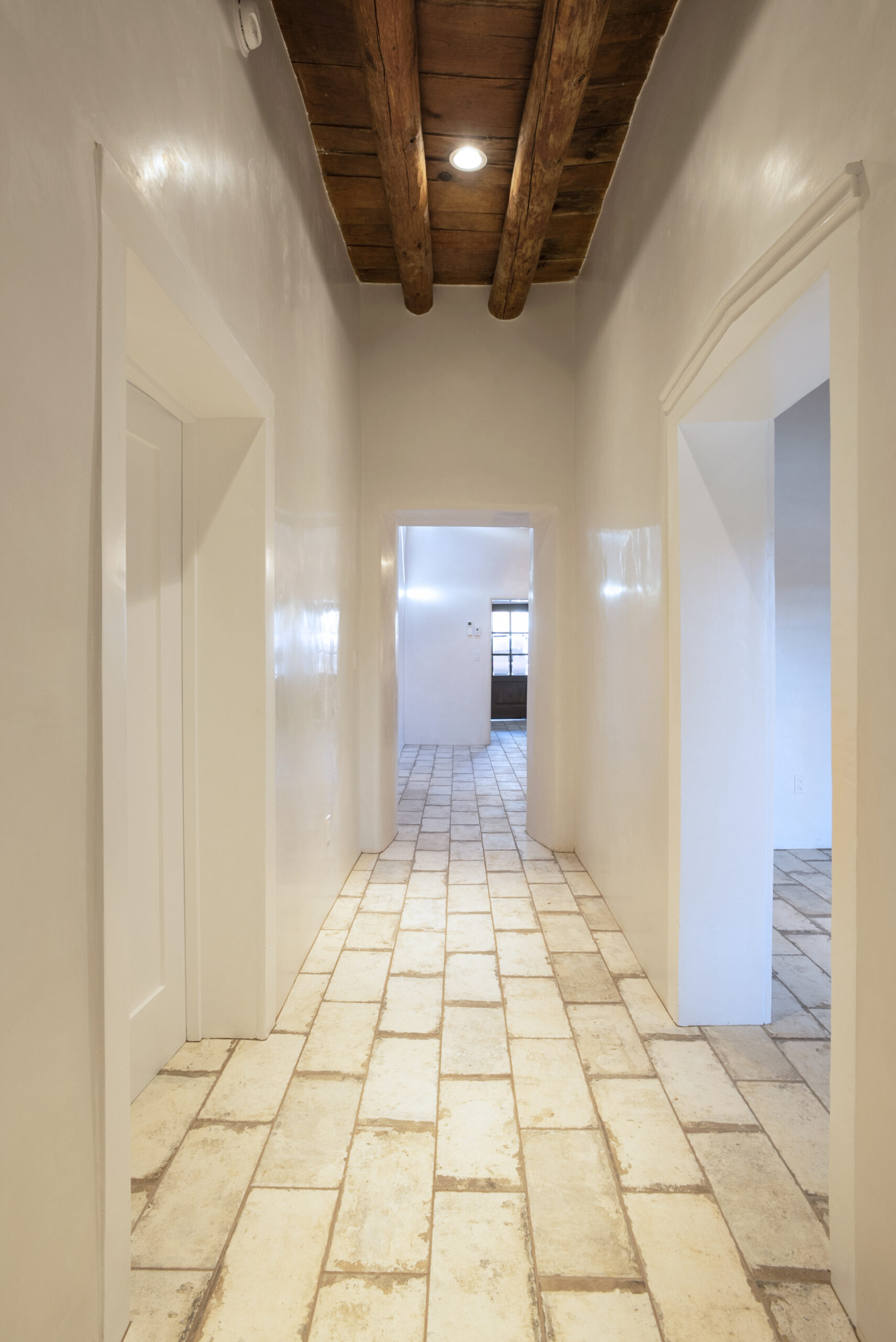 Bright hallway with tiled floor and wooden ceiling beams.