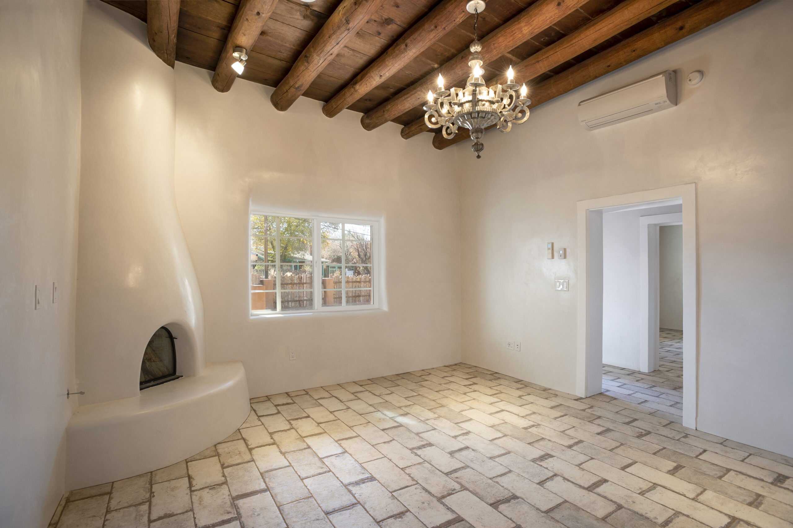 Empty room with rustic tile floor and wooden beam ceiling.