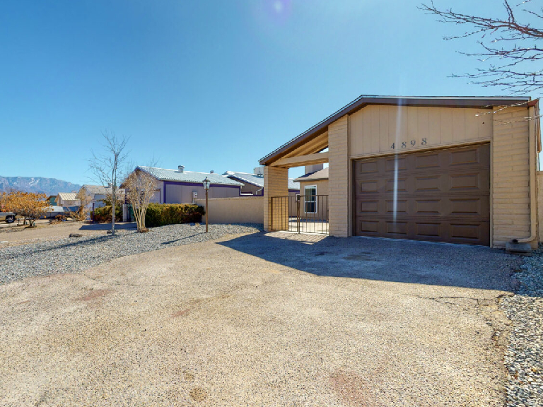 Suburban house with large driveway and clear blue sky.