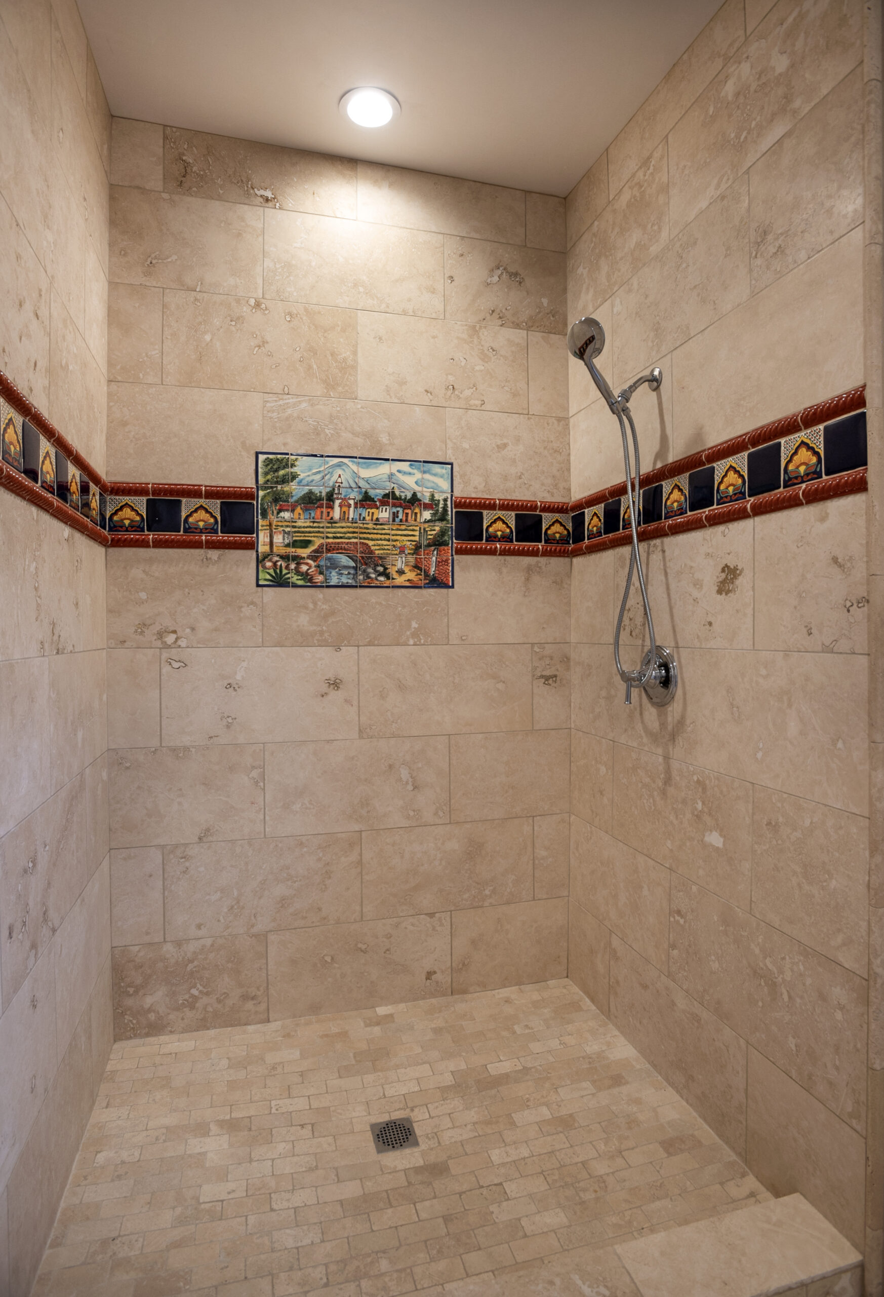 A tiled shower area with decorative border and wall art.