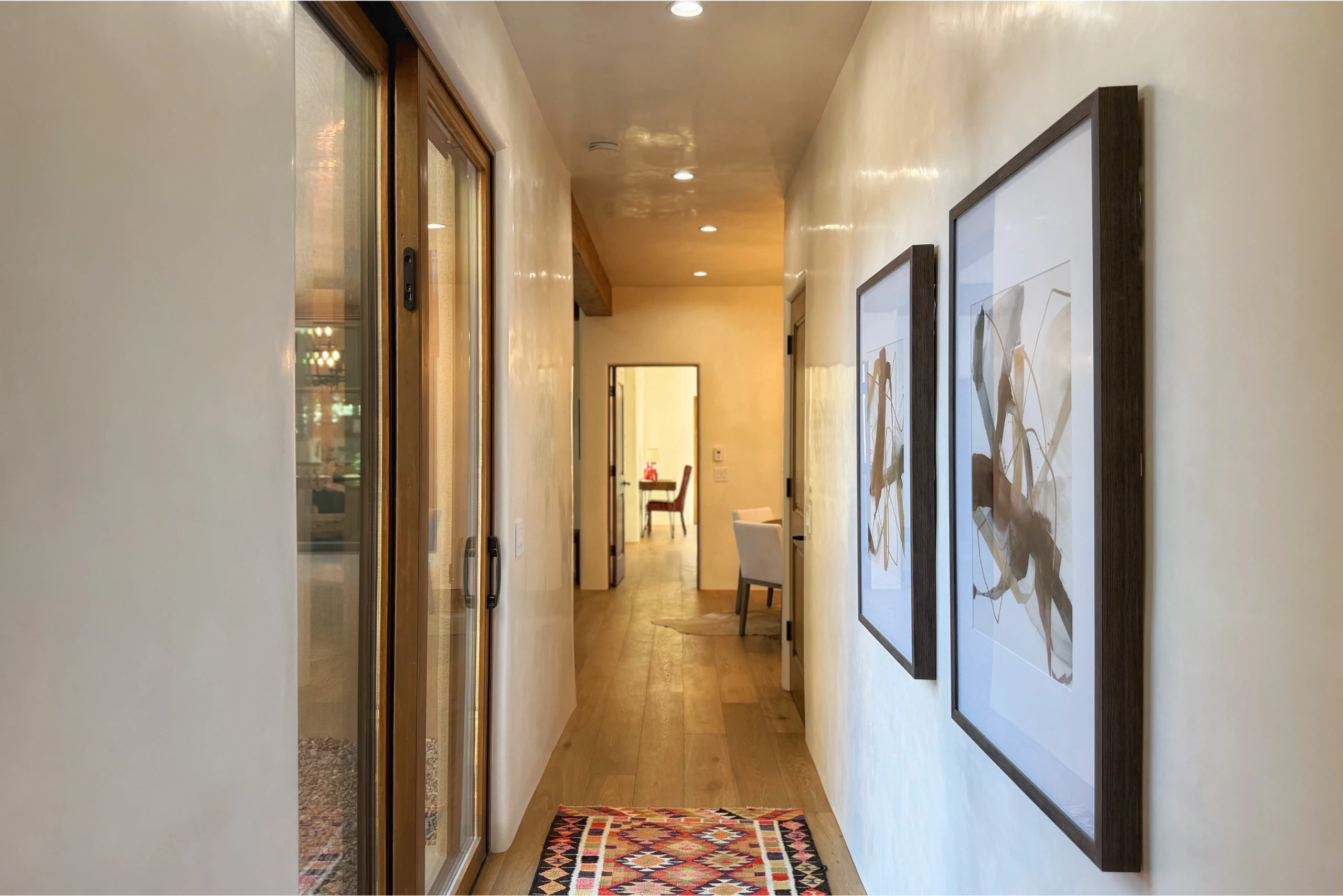 Modern hallway with framed art and a patterned rug.