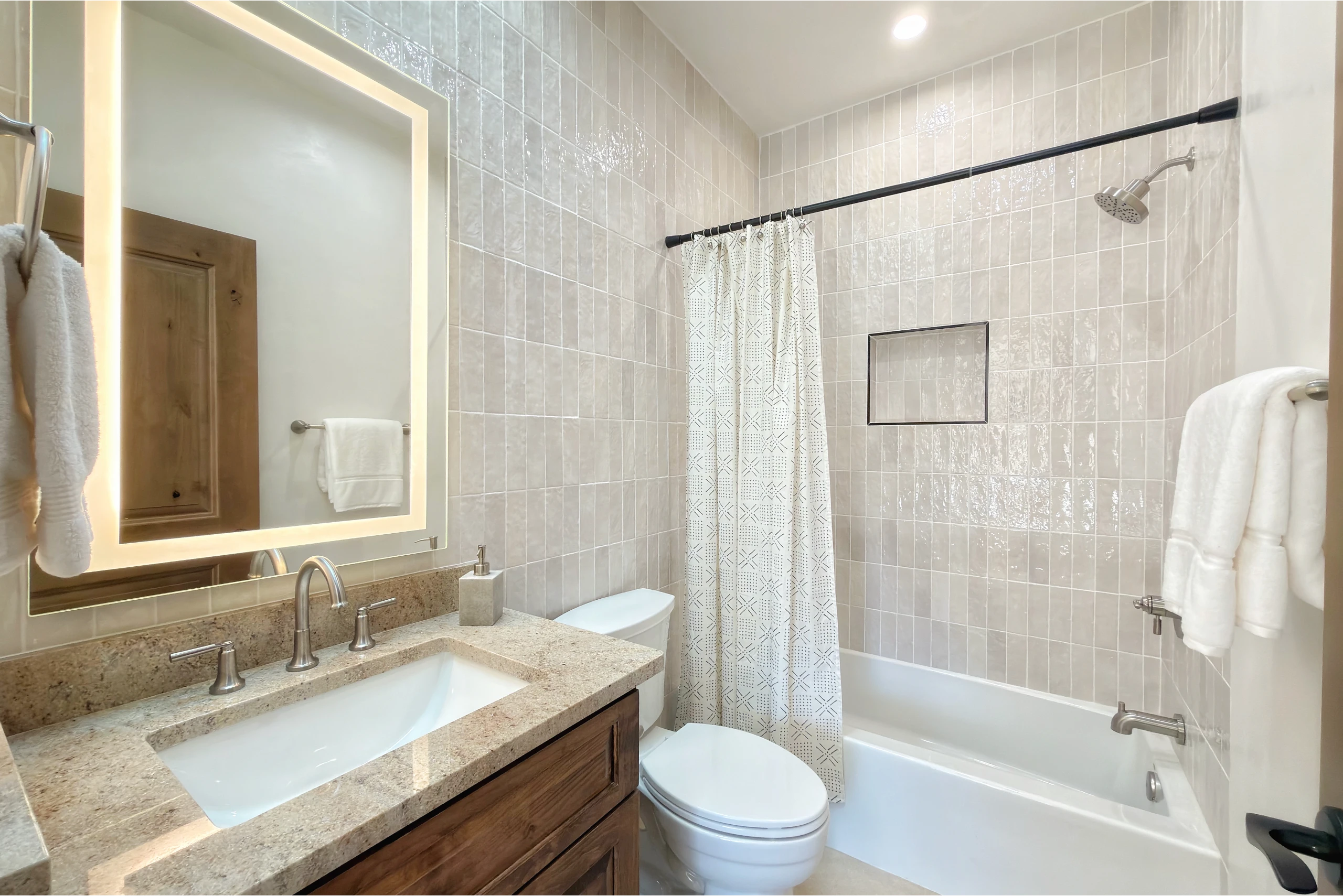 Bright bathroom with marble countertop and tiled walls.