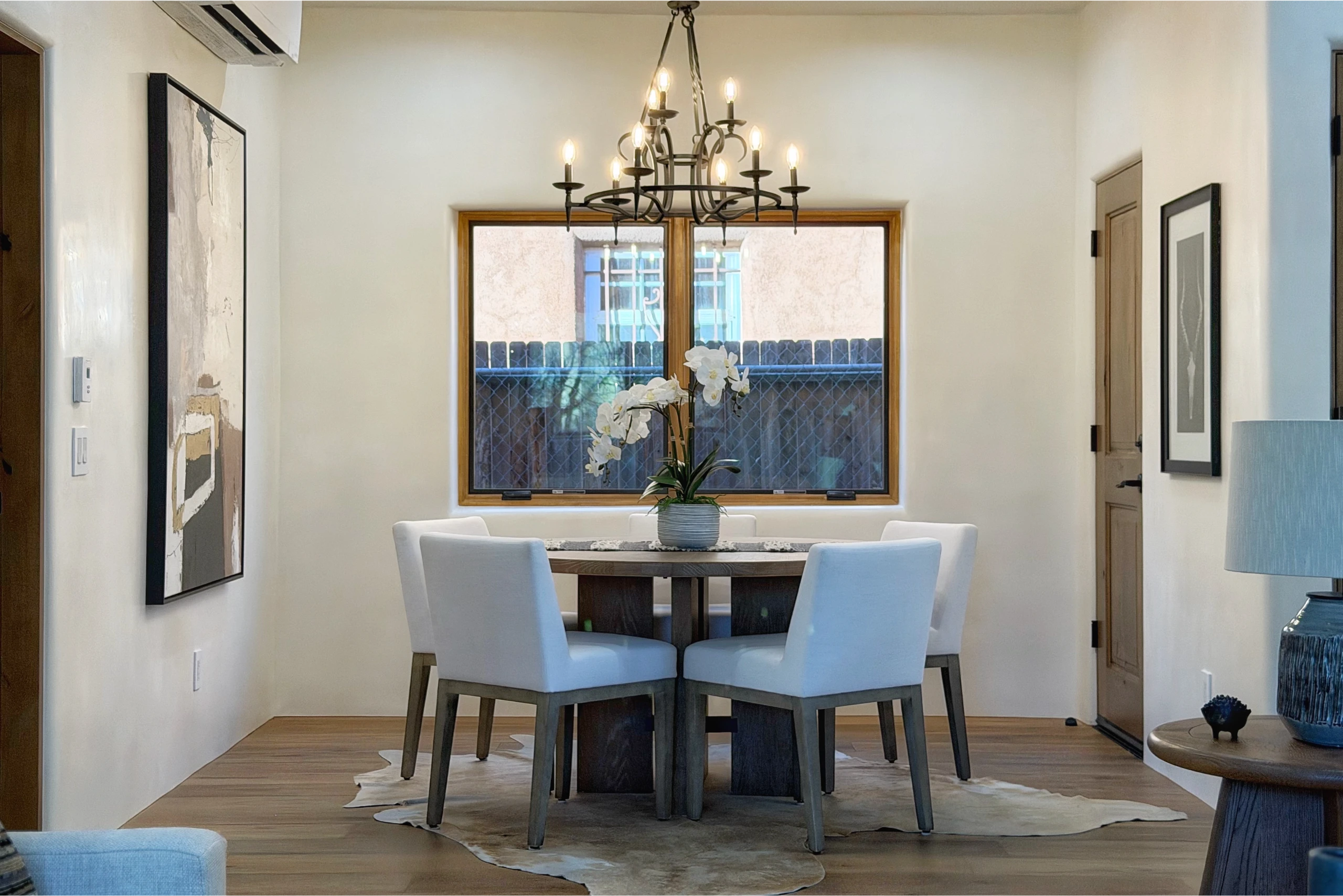Modern dining area with white chairs and a chandelier.