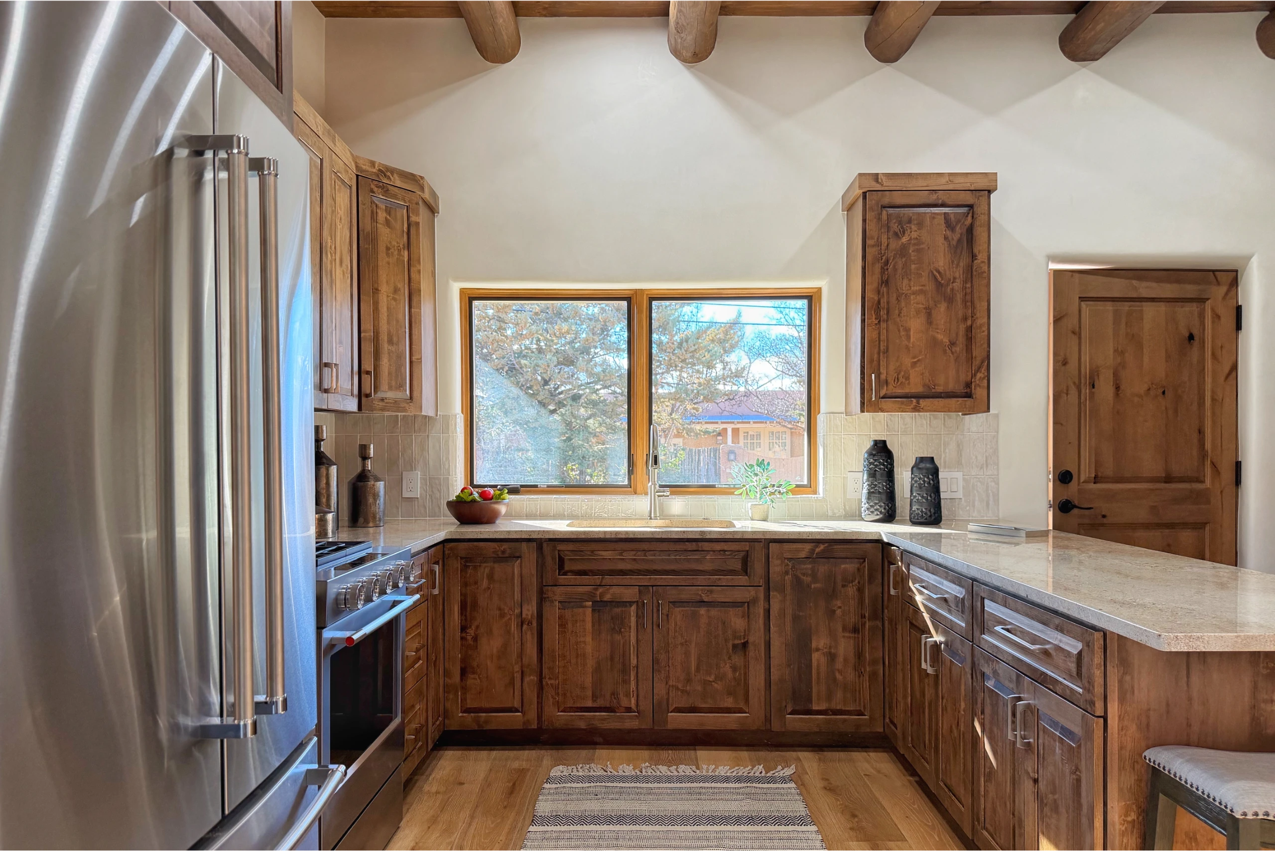 Rustic kitchen with wooden cabinets and large window.