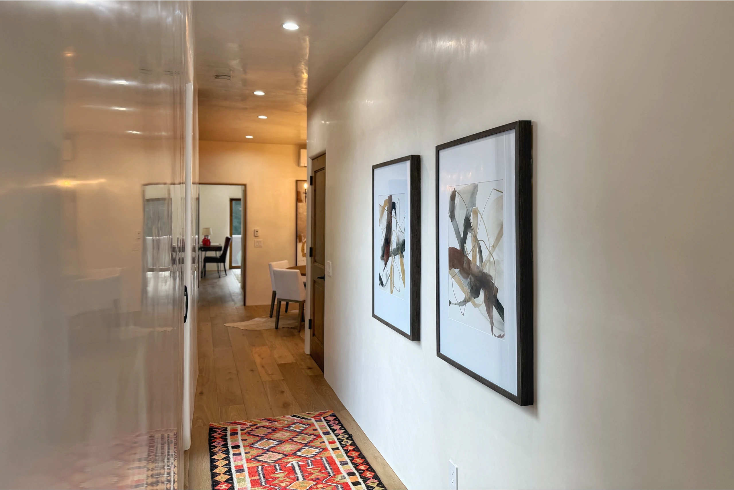 Modern hallway with framed art and a colorful rug.
