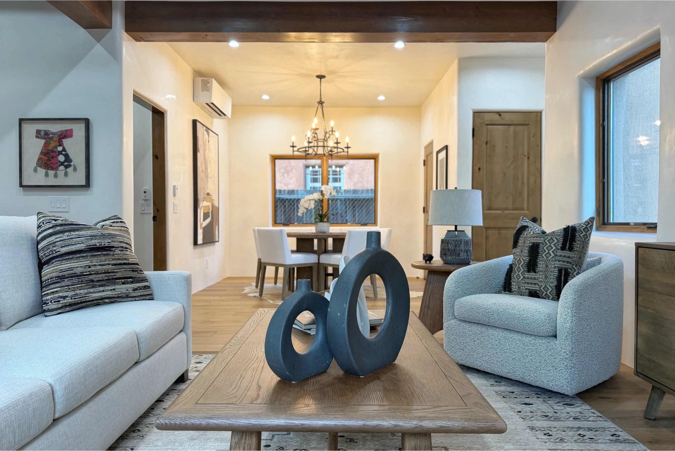 Modern living room with cozy sofas and artistic decor on a wooden coffee table.