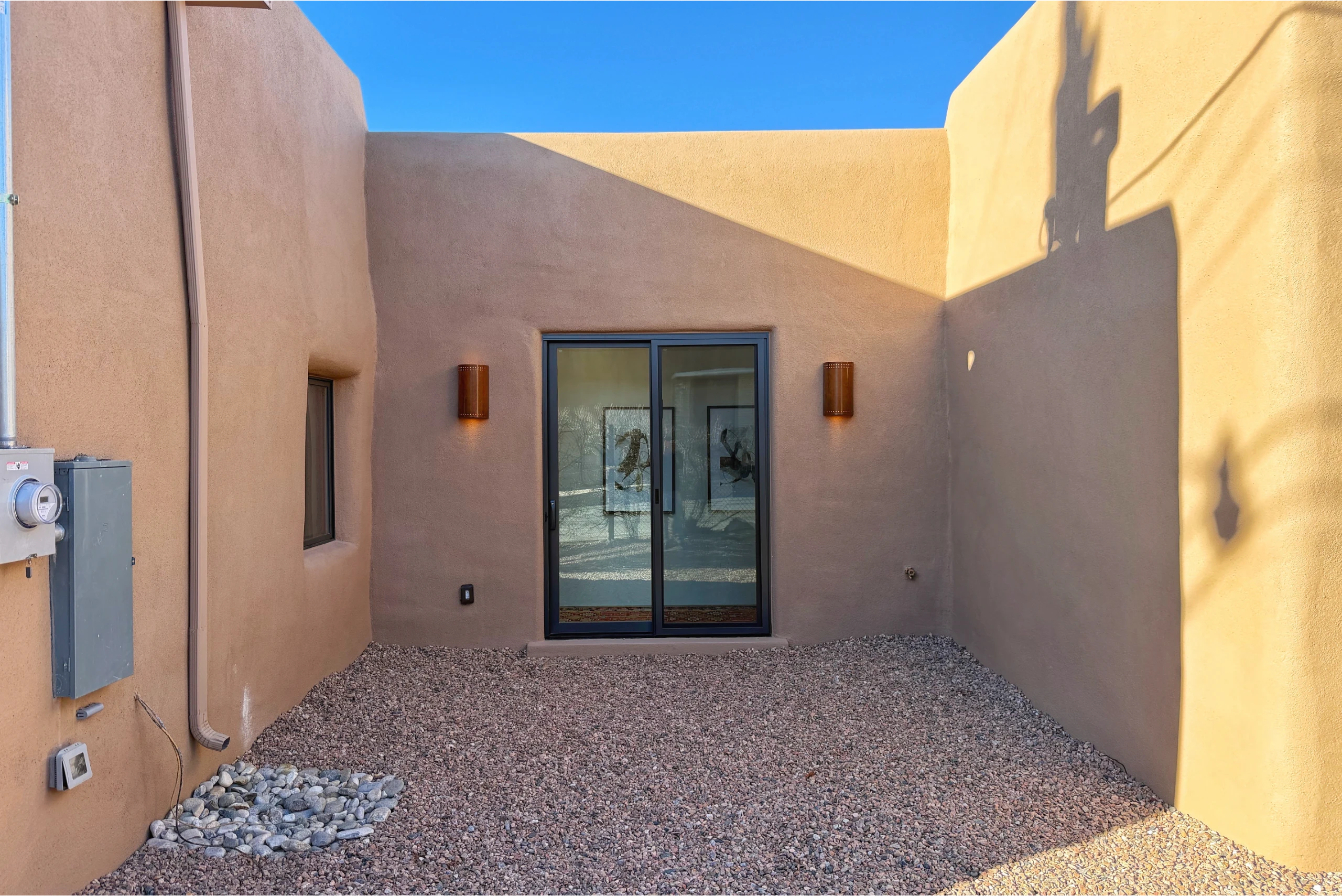 Modern adobe-style entrance with glass door and stucco walls.
