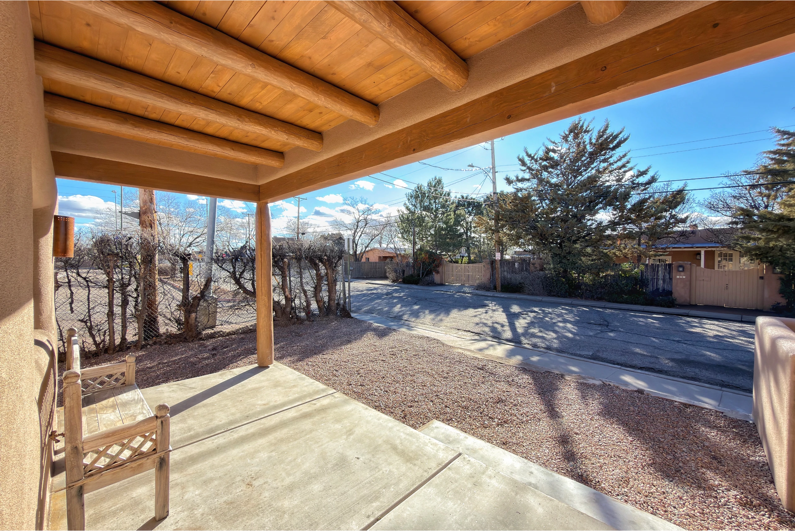 Covered patio overlooking a spacious backyard with trees and clear sky.