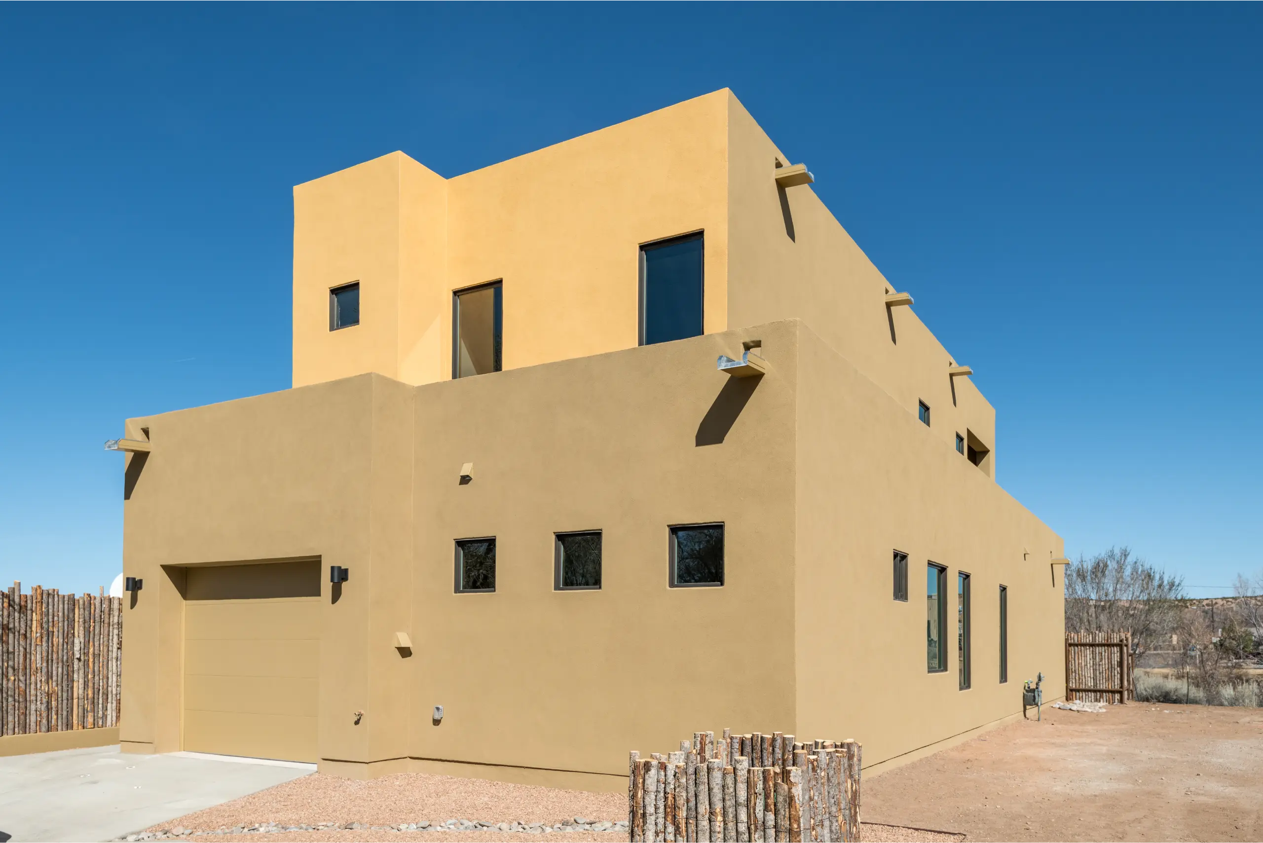 Modern beige stucco house under clear blue sky.