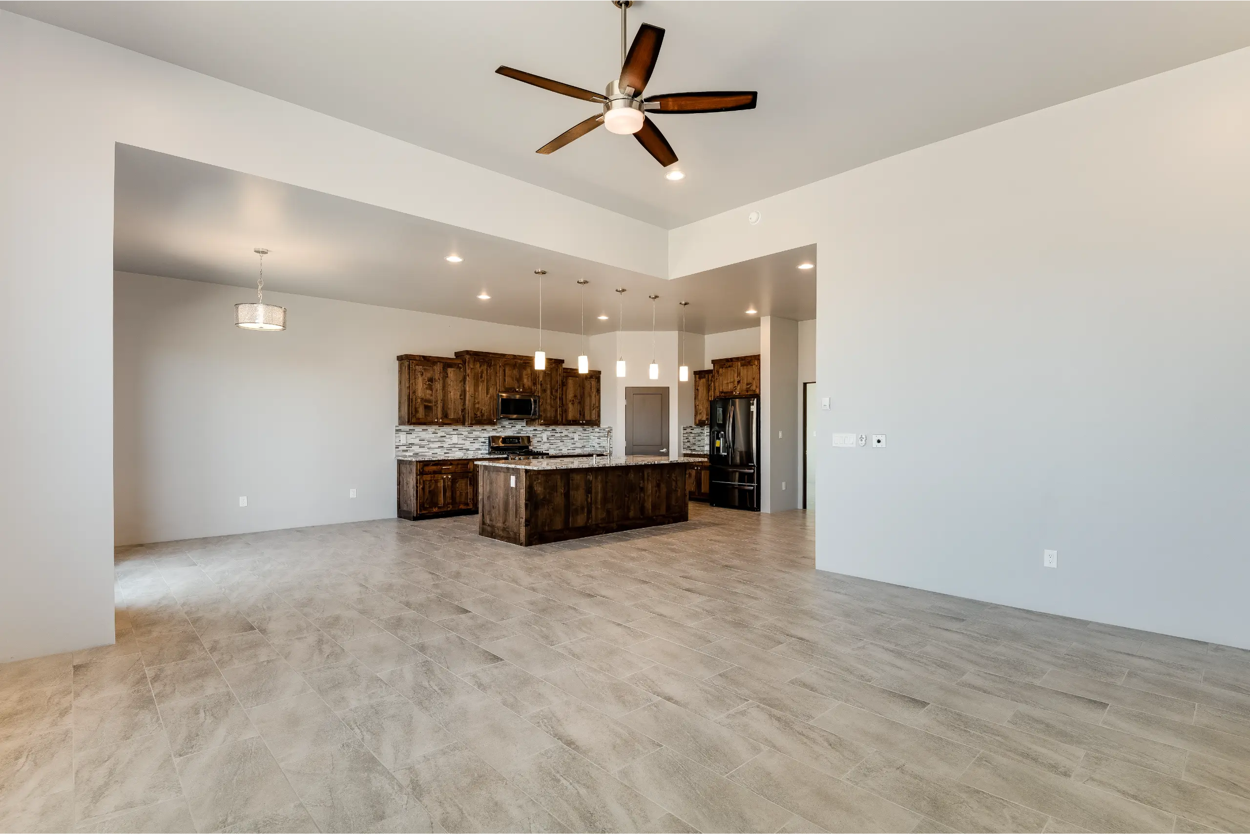 Spacious open-concept kitchen and living area with modern finishes and ceiling fan.