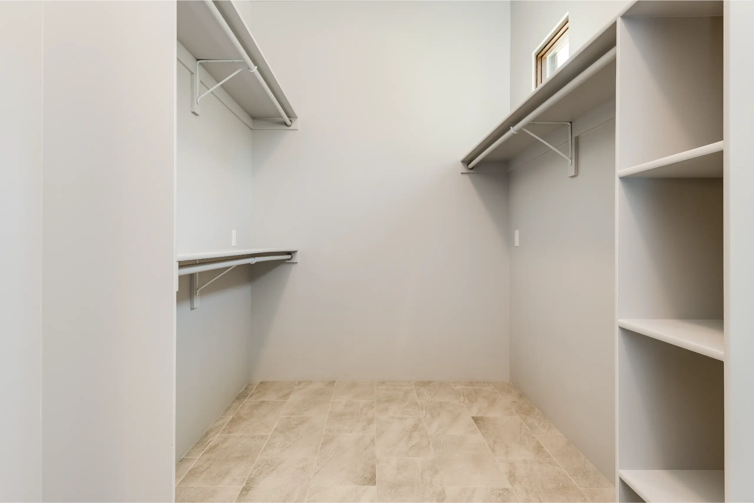 Empty walk-in closet with wooden floor and white shelves.